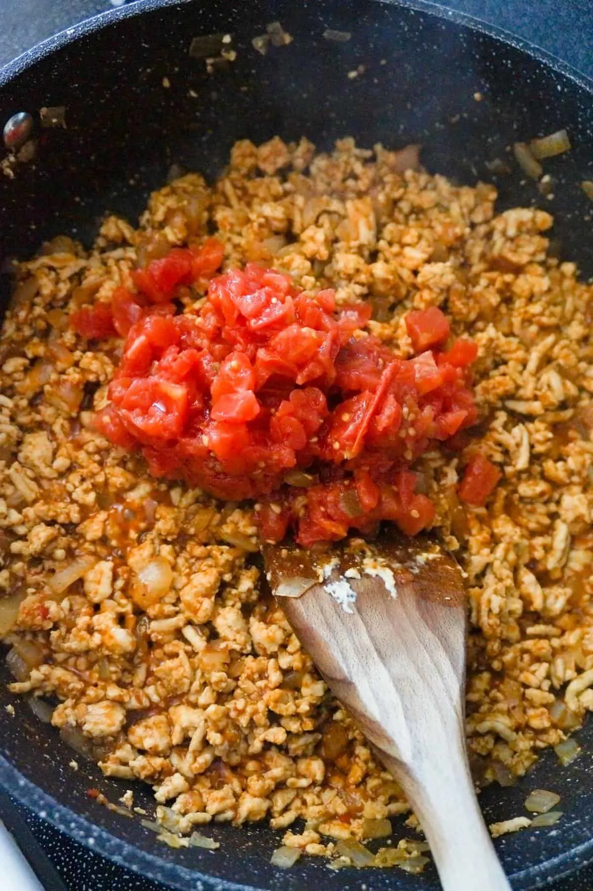 Rotel on top of ground chicken taco meat mixture in a saute pan