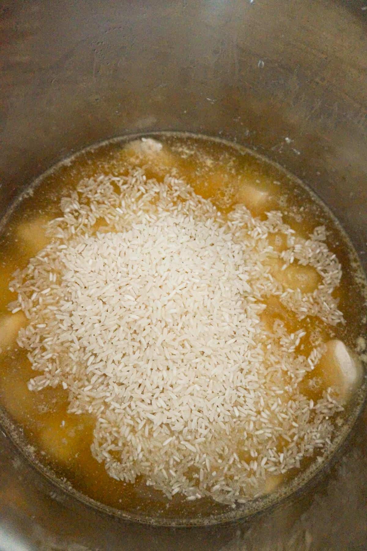 long grain white rice on top of chicken breast chunks in broth in an Instant Pot