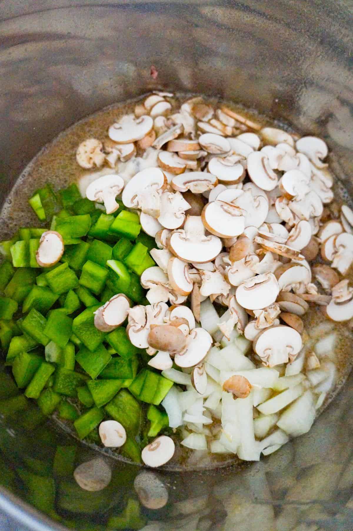 diced green peppers and sliced mushrooms on top of macaroni in an Instant Pot