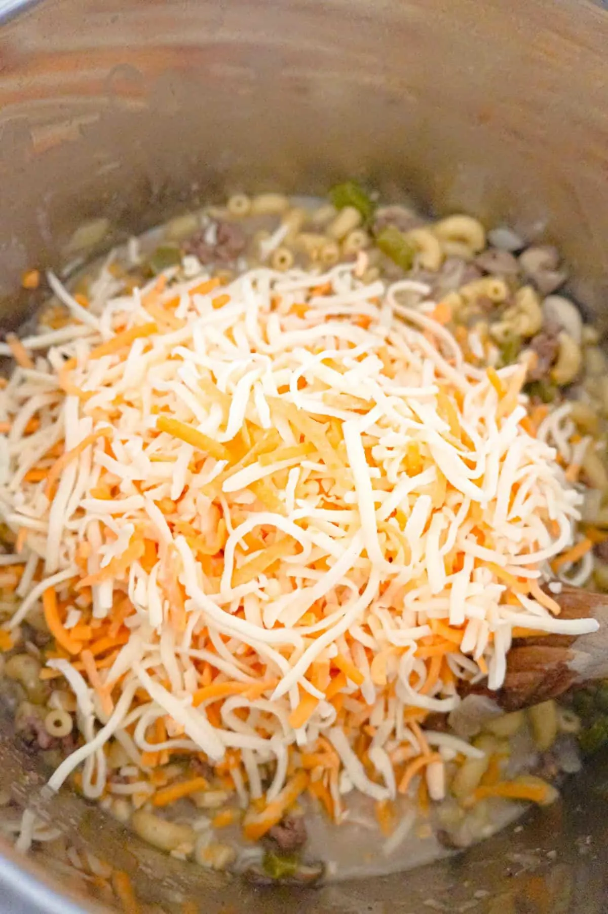 shredded mozzarella and cheddar cheese on top of hamburger macaroni in an Instant Pot