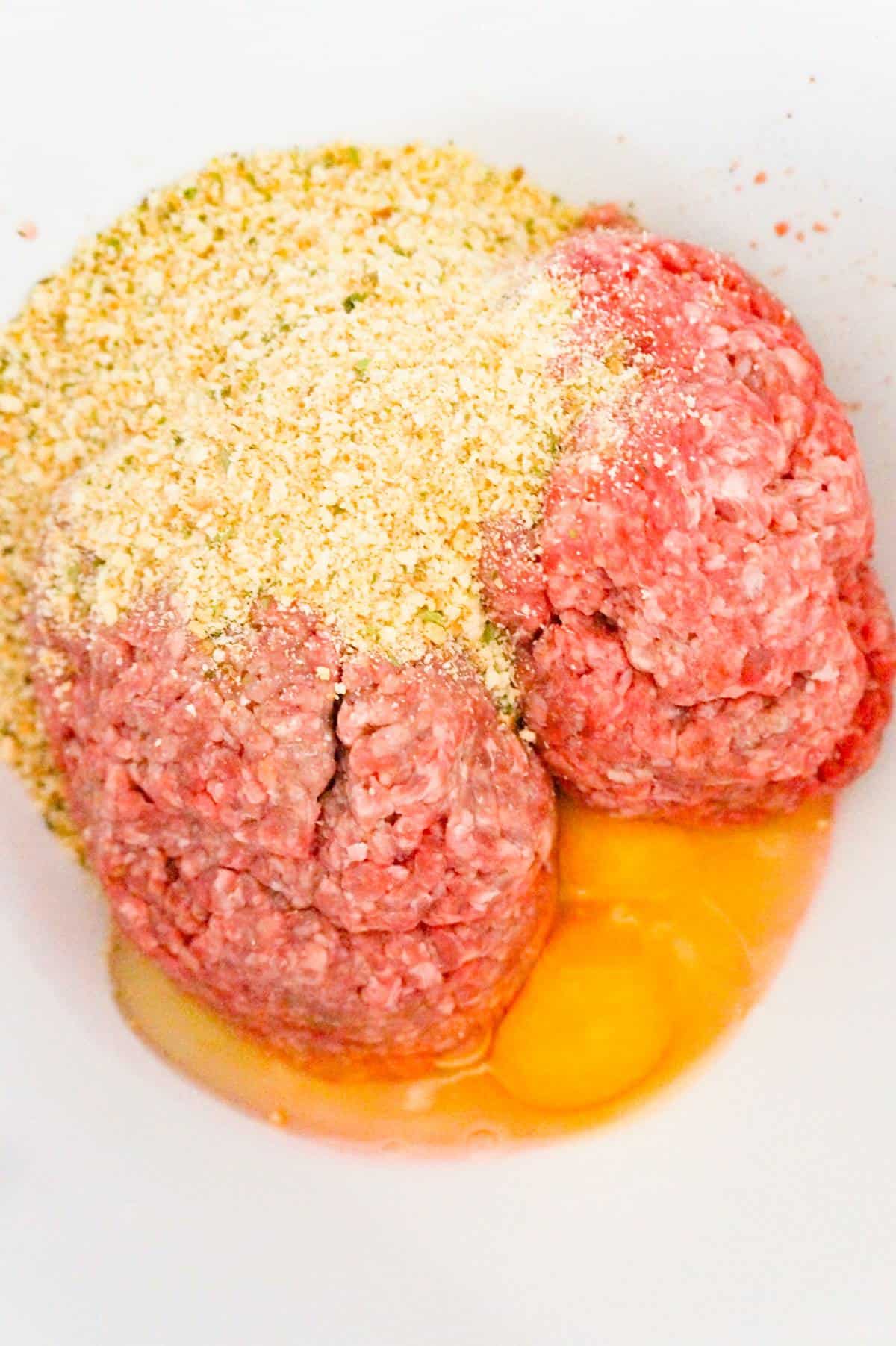 Italian bread crumbs, eggs and raw ground beef in a mixing bowl