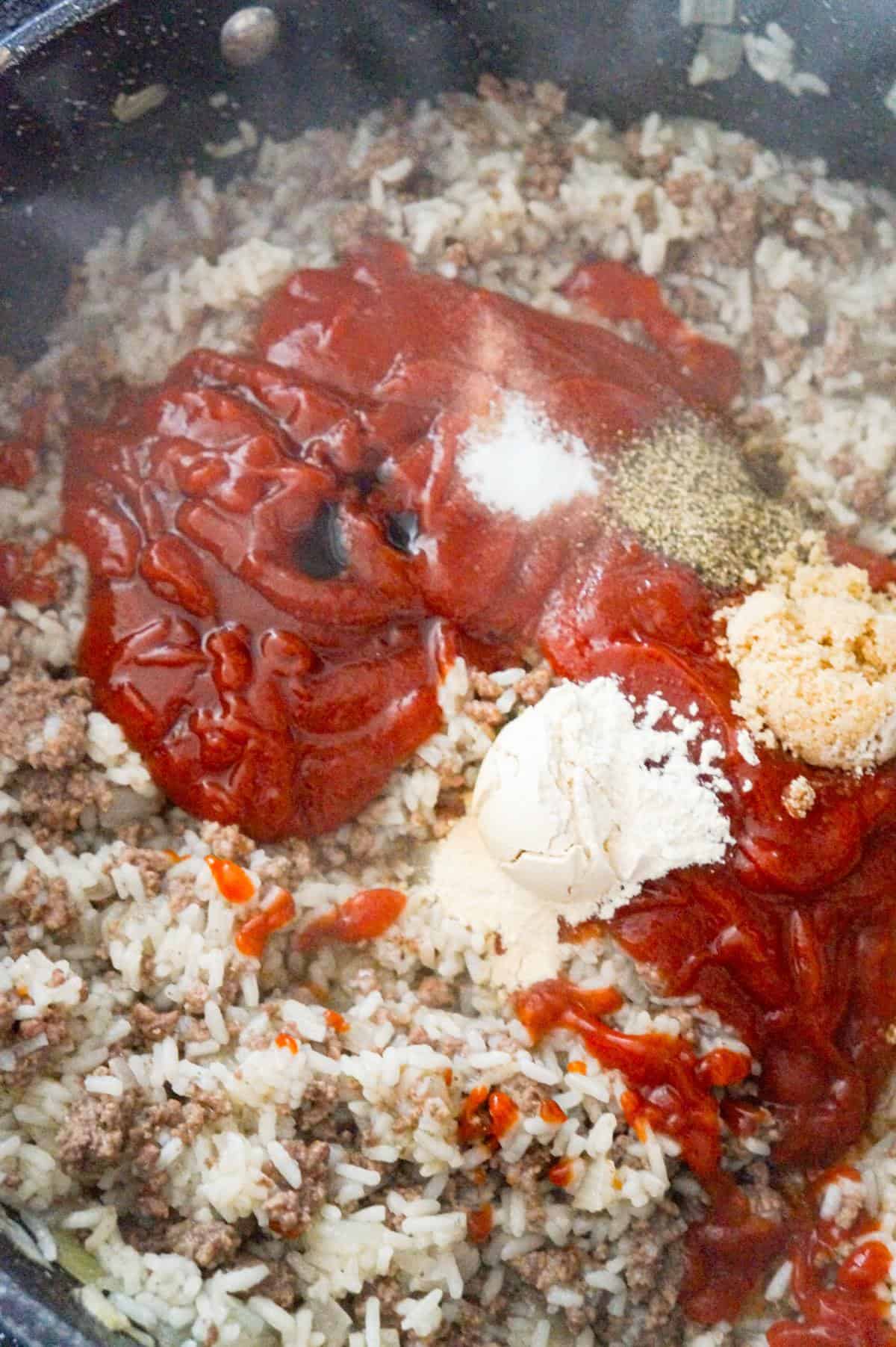ketchup and spices on top of ground beef and rice in a saute pan