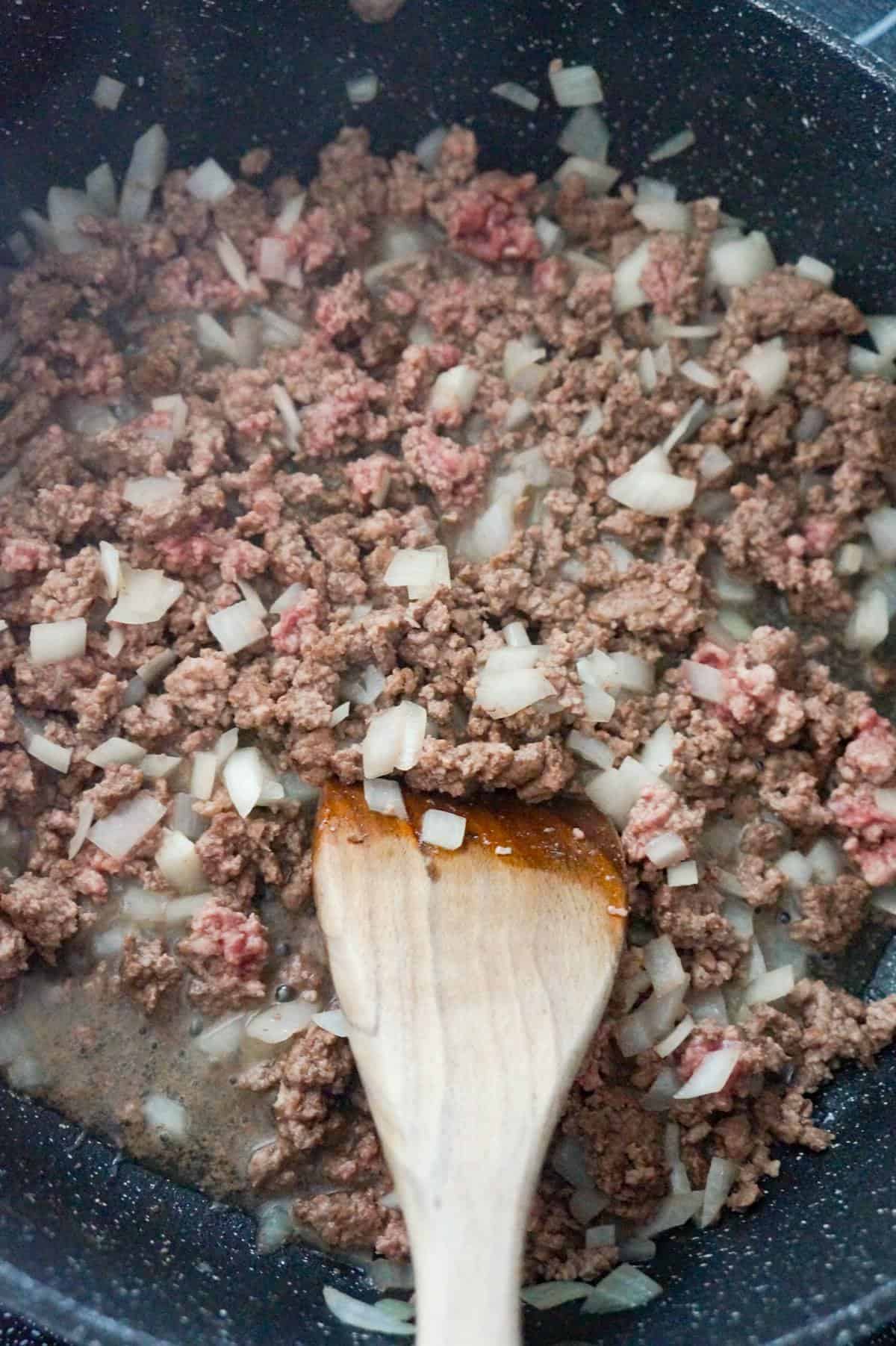 ground beef and diced onions cooking in a saute pan