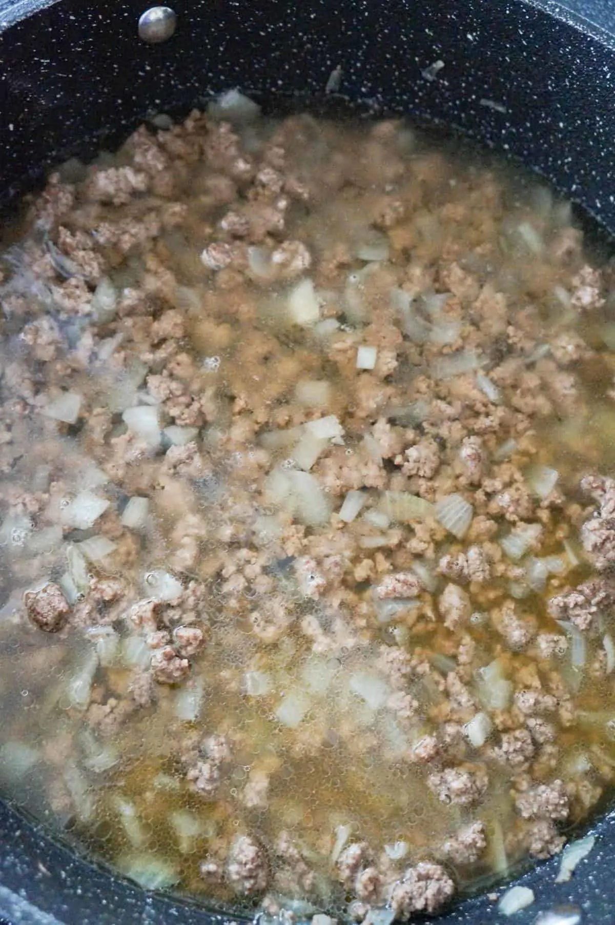 cooked ground beef and chicken broth in a saute pan