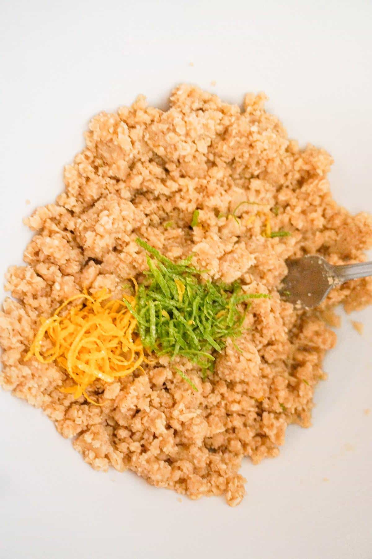 lemon zest and lime zest on top of crumble topping mixture in a mixing bowl