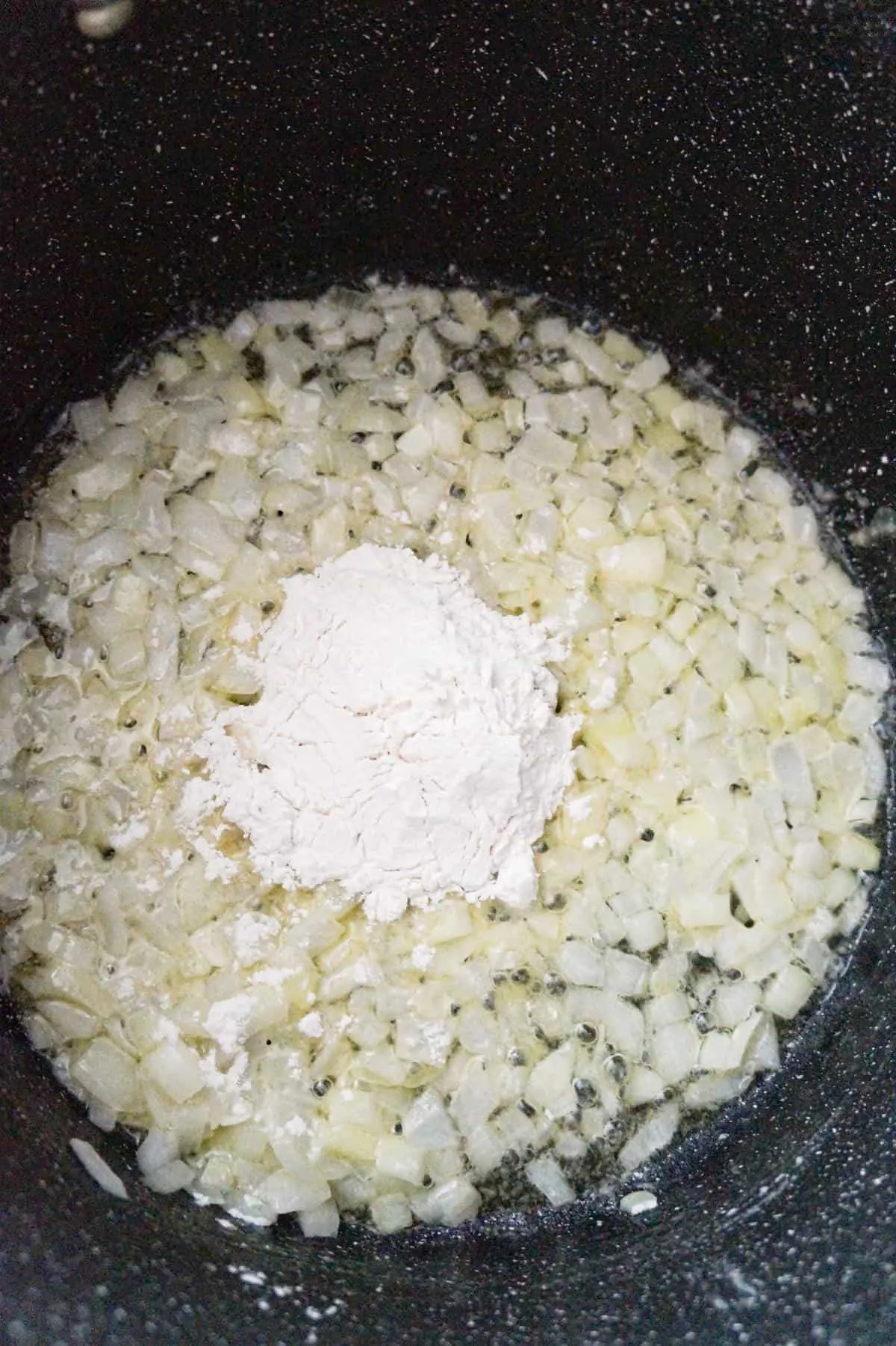 all purpose flour on top of diced onions cooking in a large pot