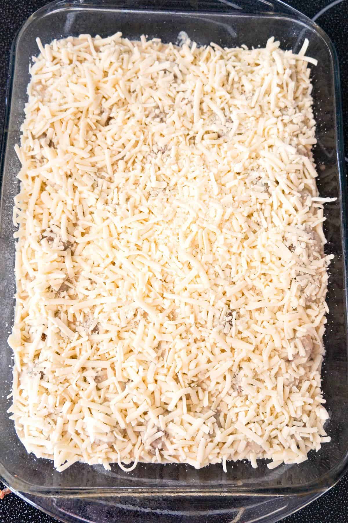 shredded mozzarella cheese on top of Swedish meatballs in a baking dish