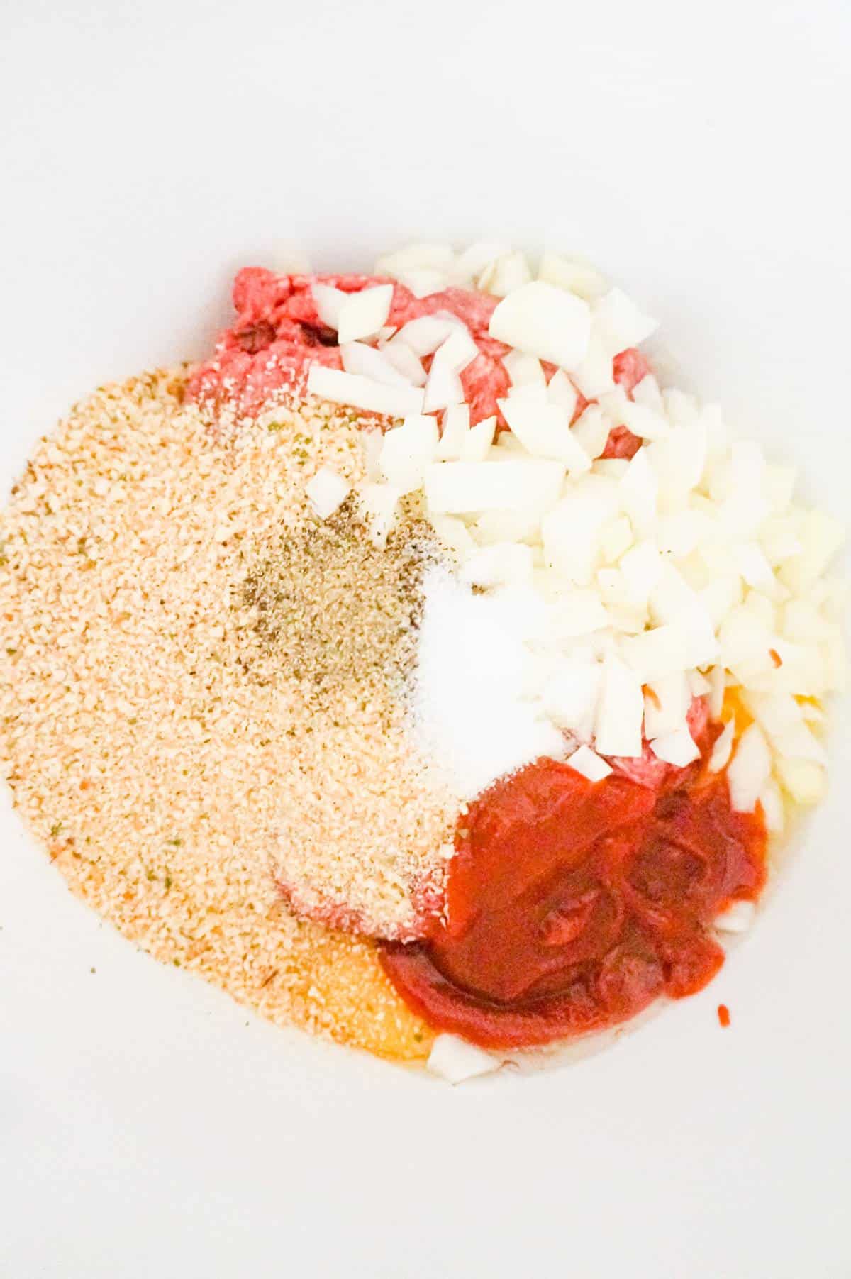 ketchup, diced onions and bread crumbs on top of ground beef in a mixing bowl