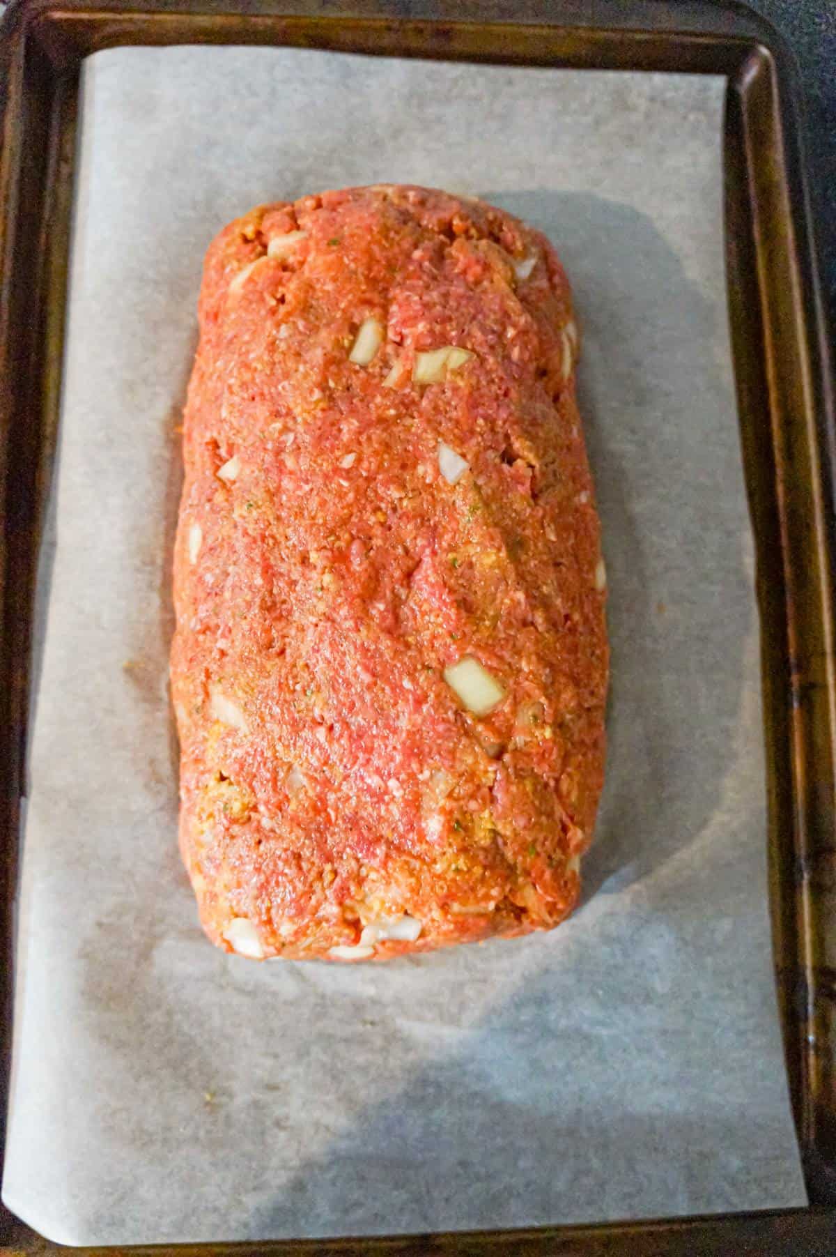 raw meatloaf on a parchment lined baking sheet