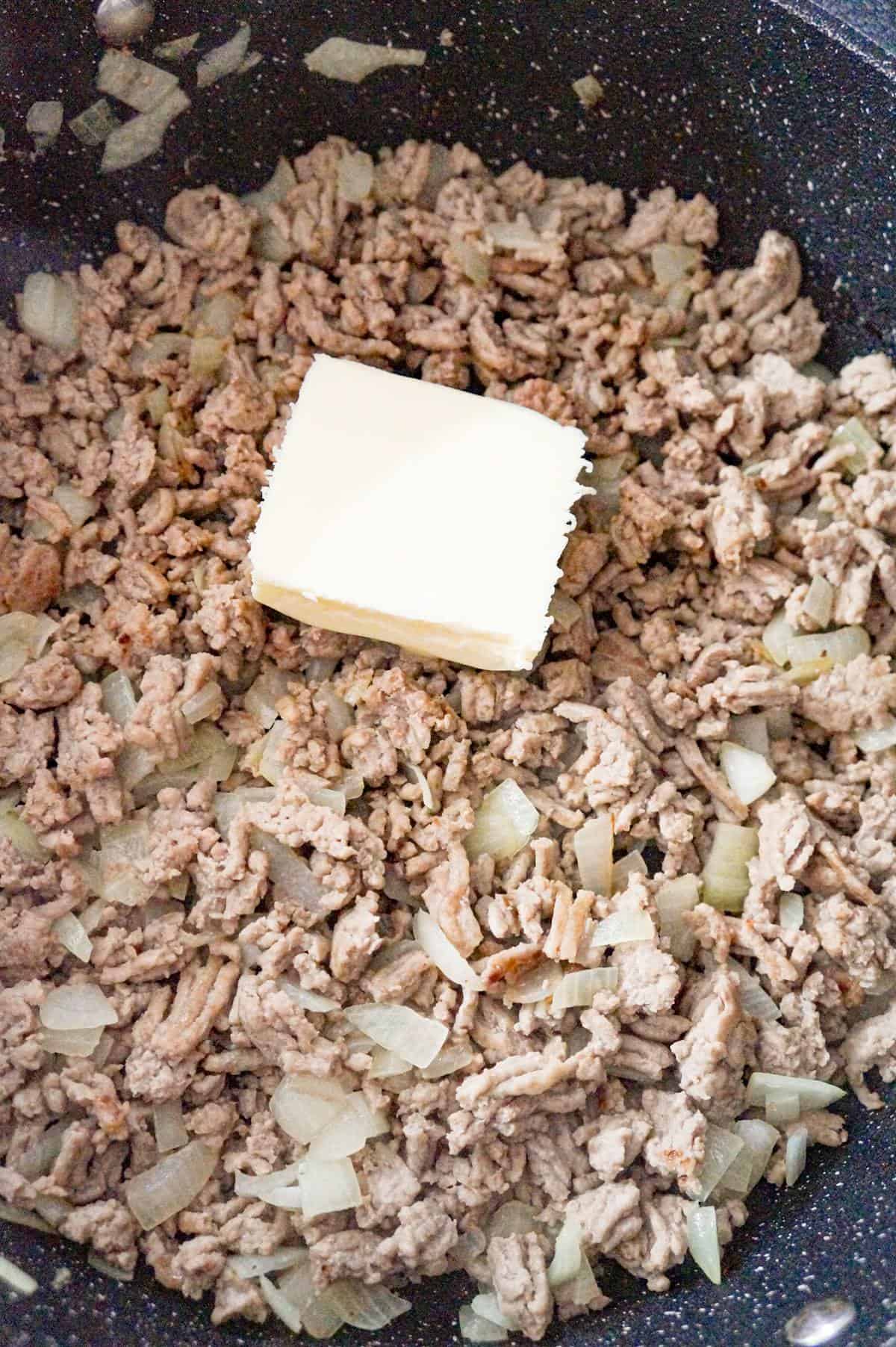 butter on top of cooked ground chicken in a saute pan