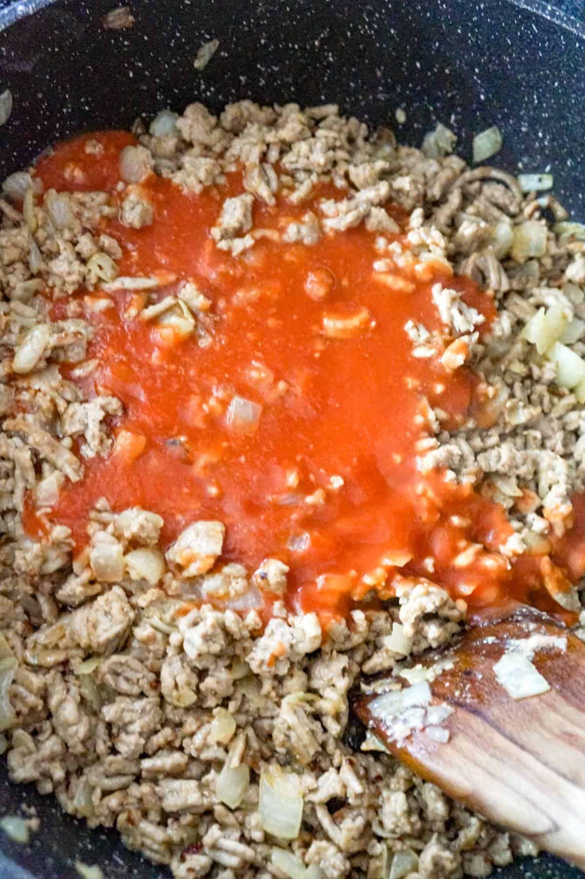 tomato sauce on top of cooked ground chicken in a saute pan