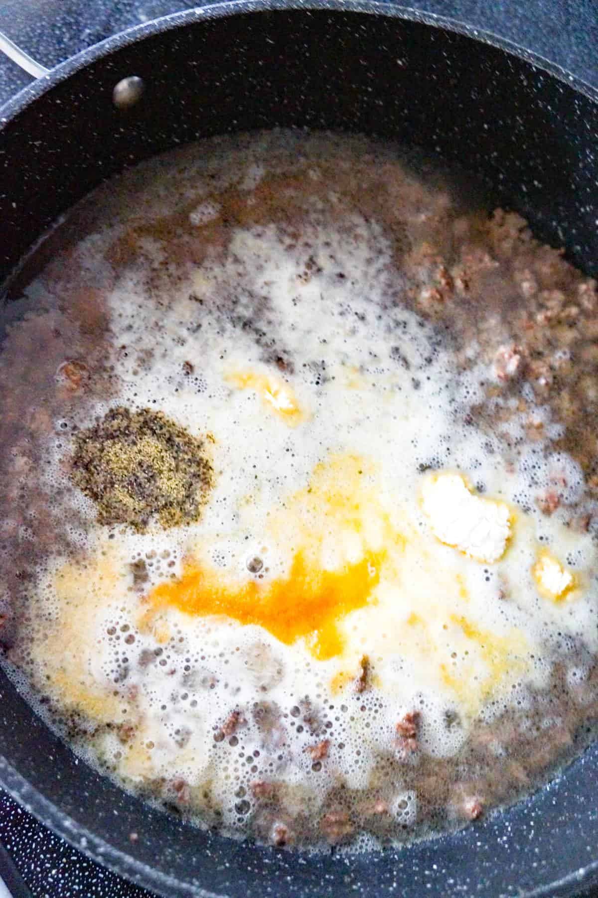spices on top of water and cooked ground beef in a pan