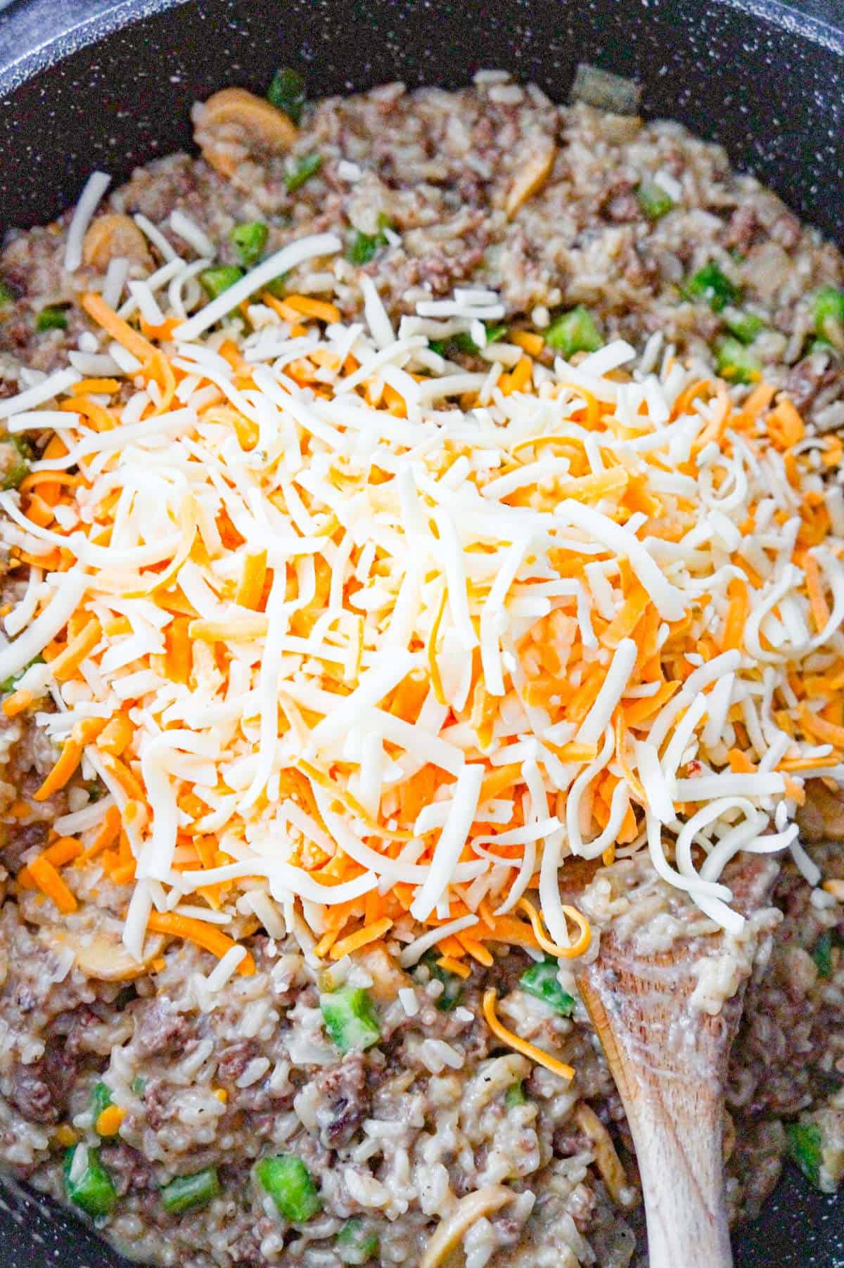 shredded cheese on top of philly cheese steak ground beef and rice before stirring