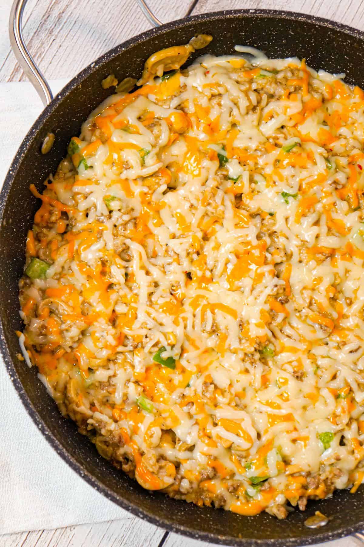One Pot Philly Cheese Steak Ground Beef and Rice is an easy stove top dinner recipe loaded with hamburger meat, green peppers, sliced mushrooms, instant rice, cream of mushroom soup and shredded cheese.