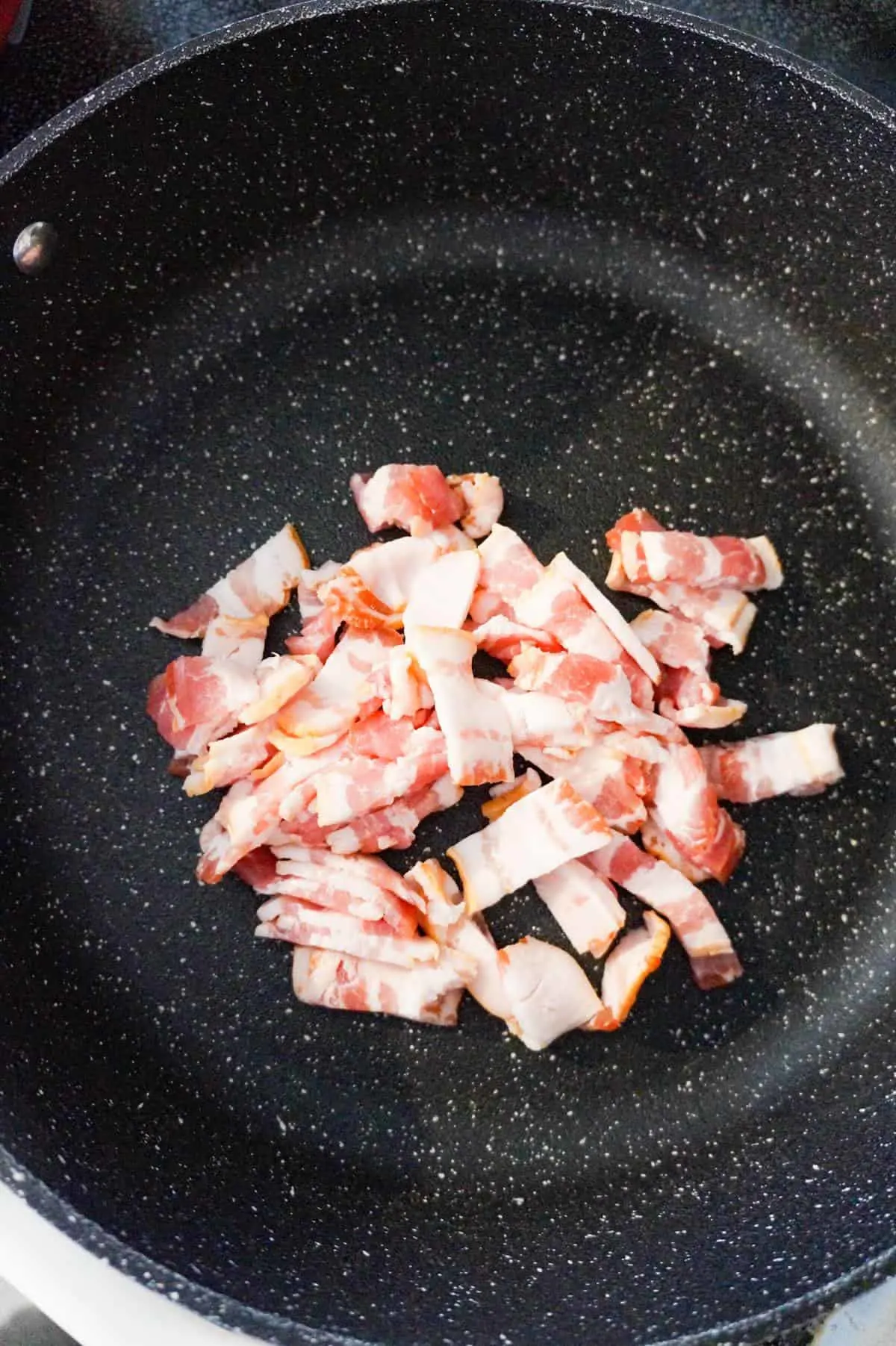 raw bacon pieces in a saute pan