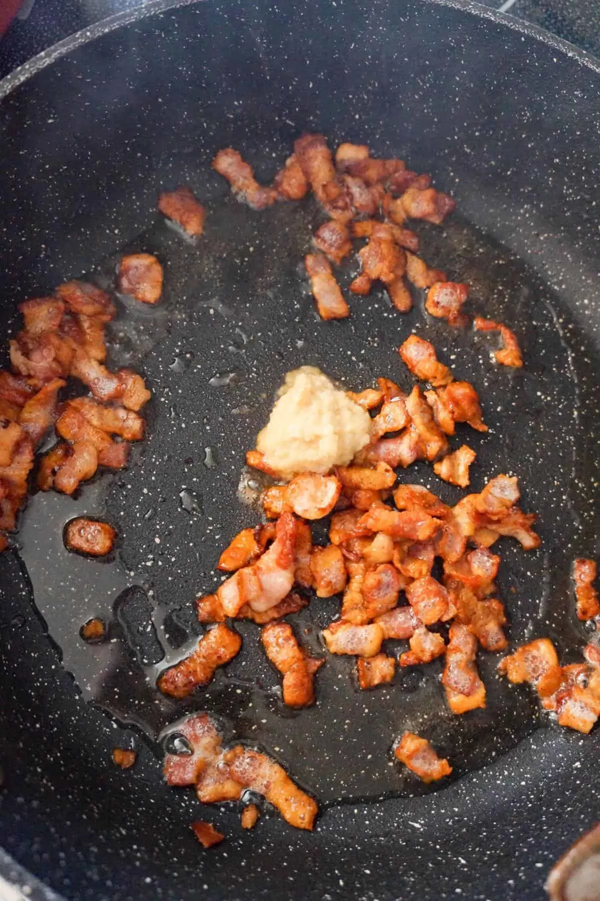garlic puree added to pan with cooked bacon pieces