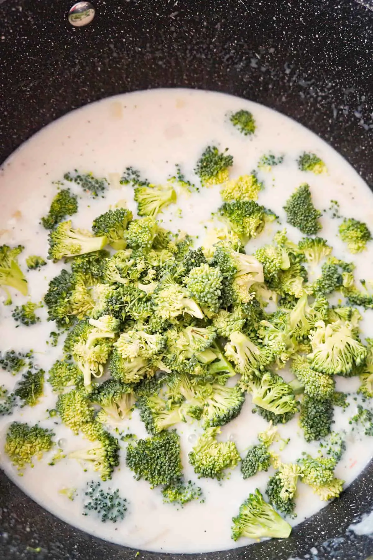 chopped broccoli florets on top of soup on a pot