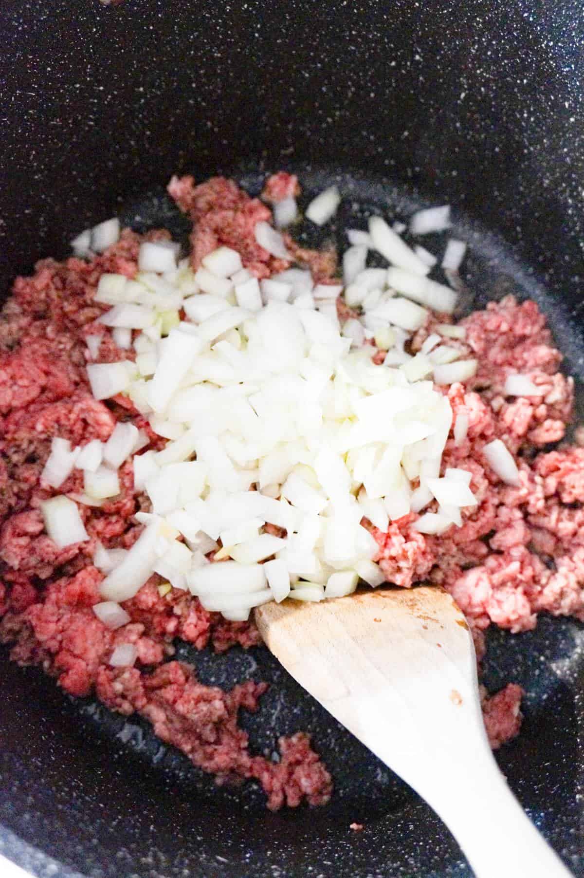 diced onions on top of raw ground in a large pot