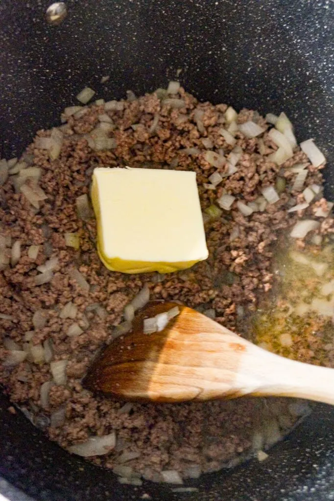 butter on top of cooked ground beef and diced onions in a large pot