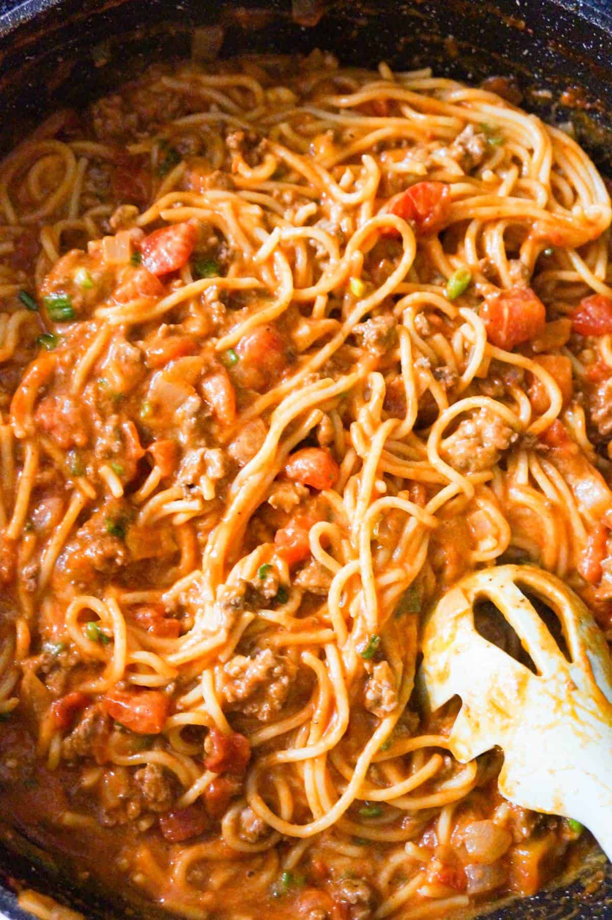 cheesy taco spaghetti being stirred in pan