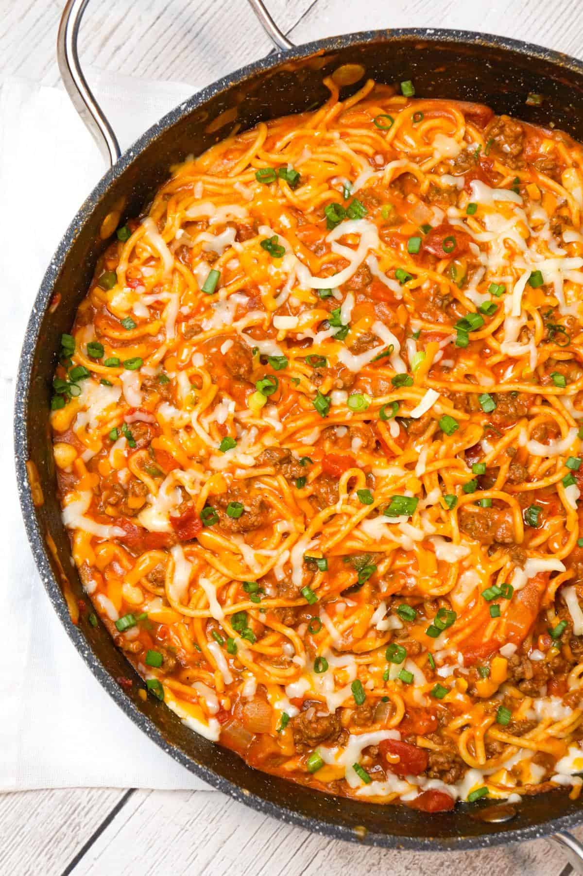 Cheesy Taco Spaghetti is an easy weeknight dinner recipe loaded with ground beef, Rotel diced tomatoes and chilies, green onions and shredded cheese all tossed in taco seasoning and tomato sauce.