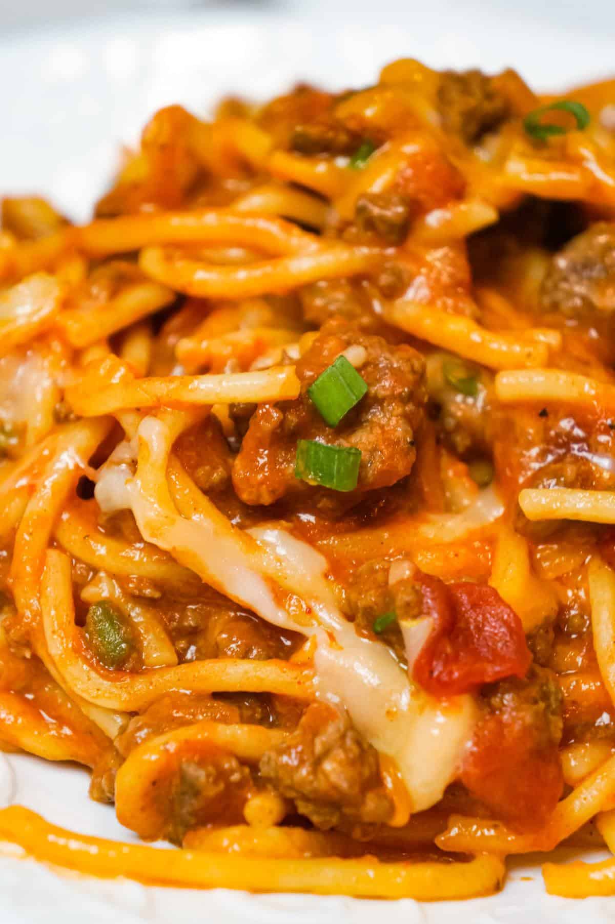 Cheesy Taco Spaghetti is an easy weeknight dinner recipe loaded with ground beef, Rotel diced tomatoes and chilies, green onions and shredded cheese all tossed in taco seasoning and tomato sauce.