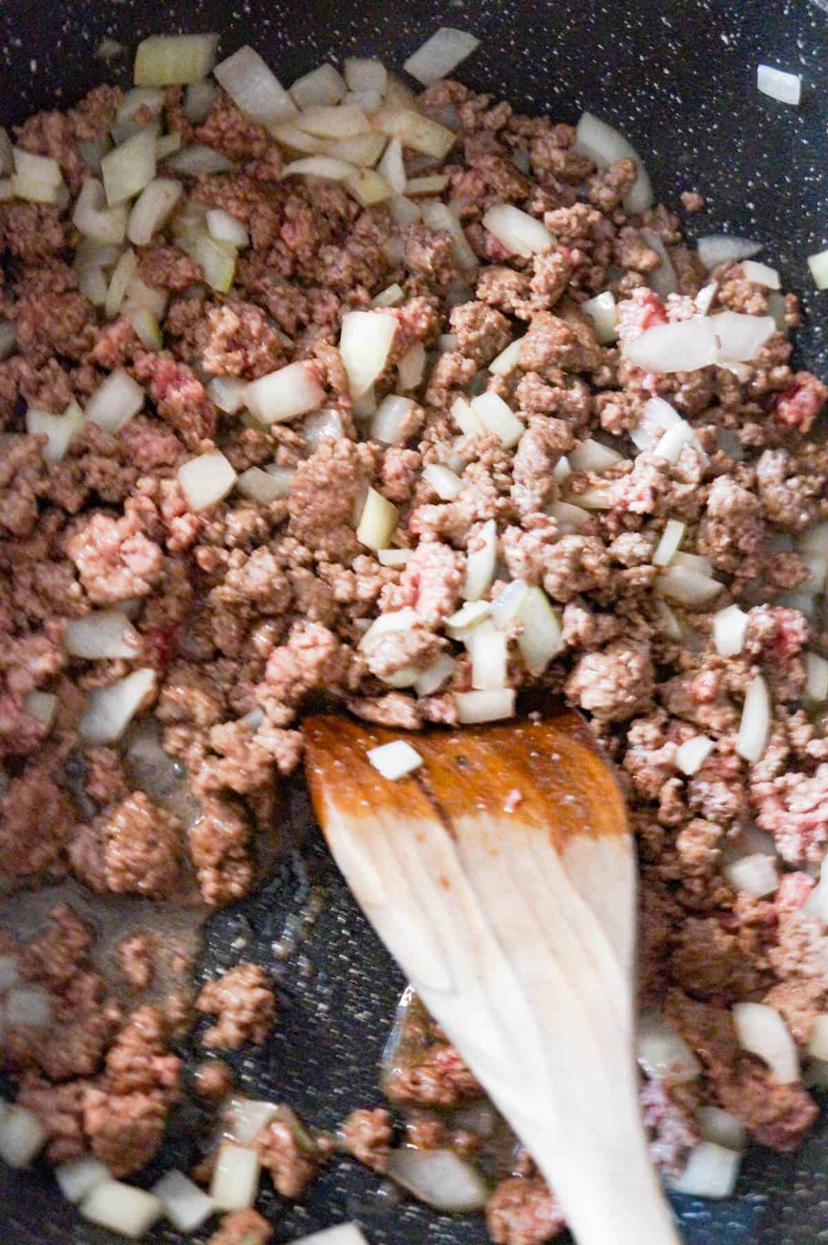 ground beef and diced onions cooking in a saute pan