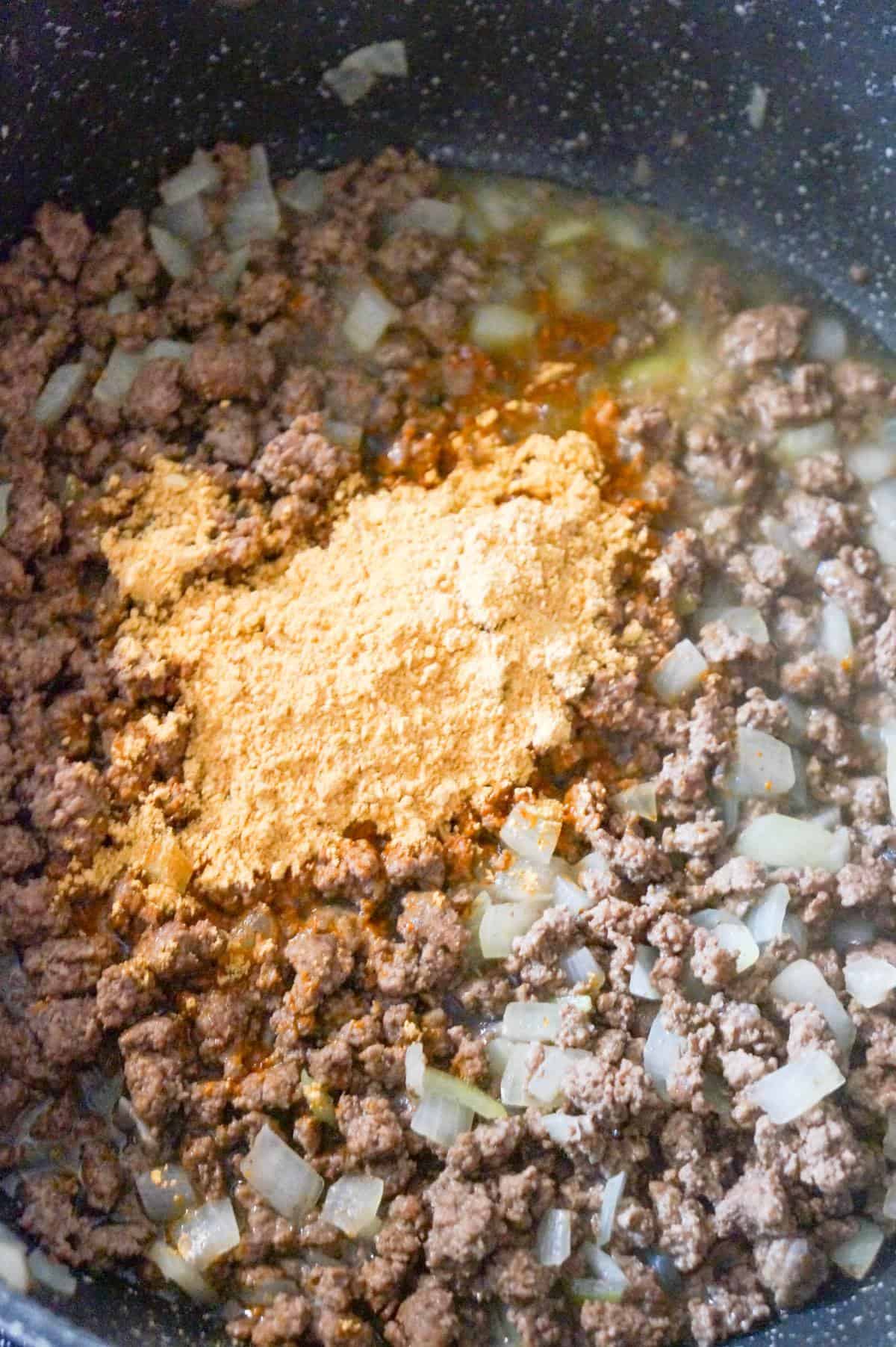 taco seasoning on top of cooked ground beef in a saute pan