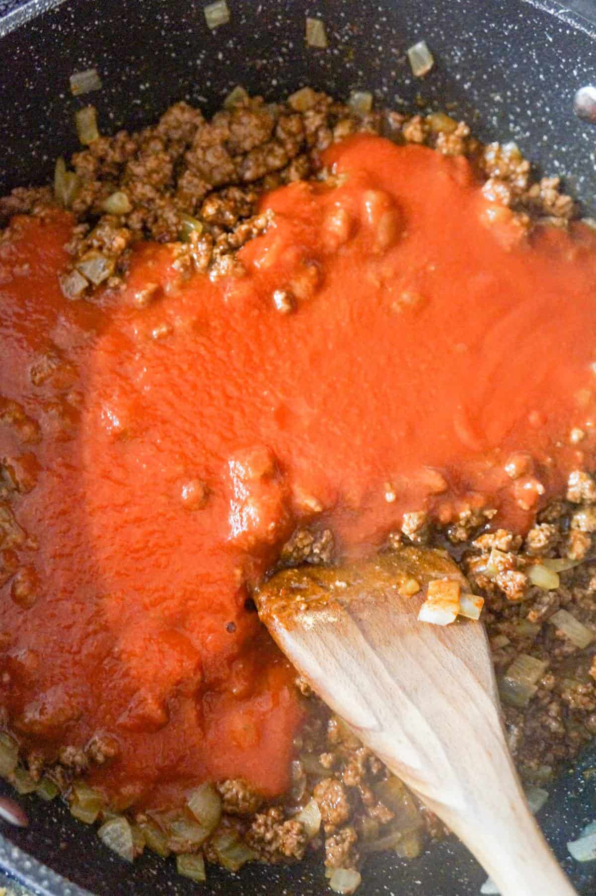 tomato sauce on top of cooked ground beef in a saute pan