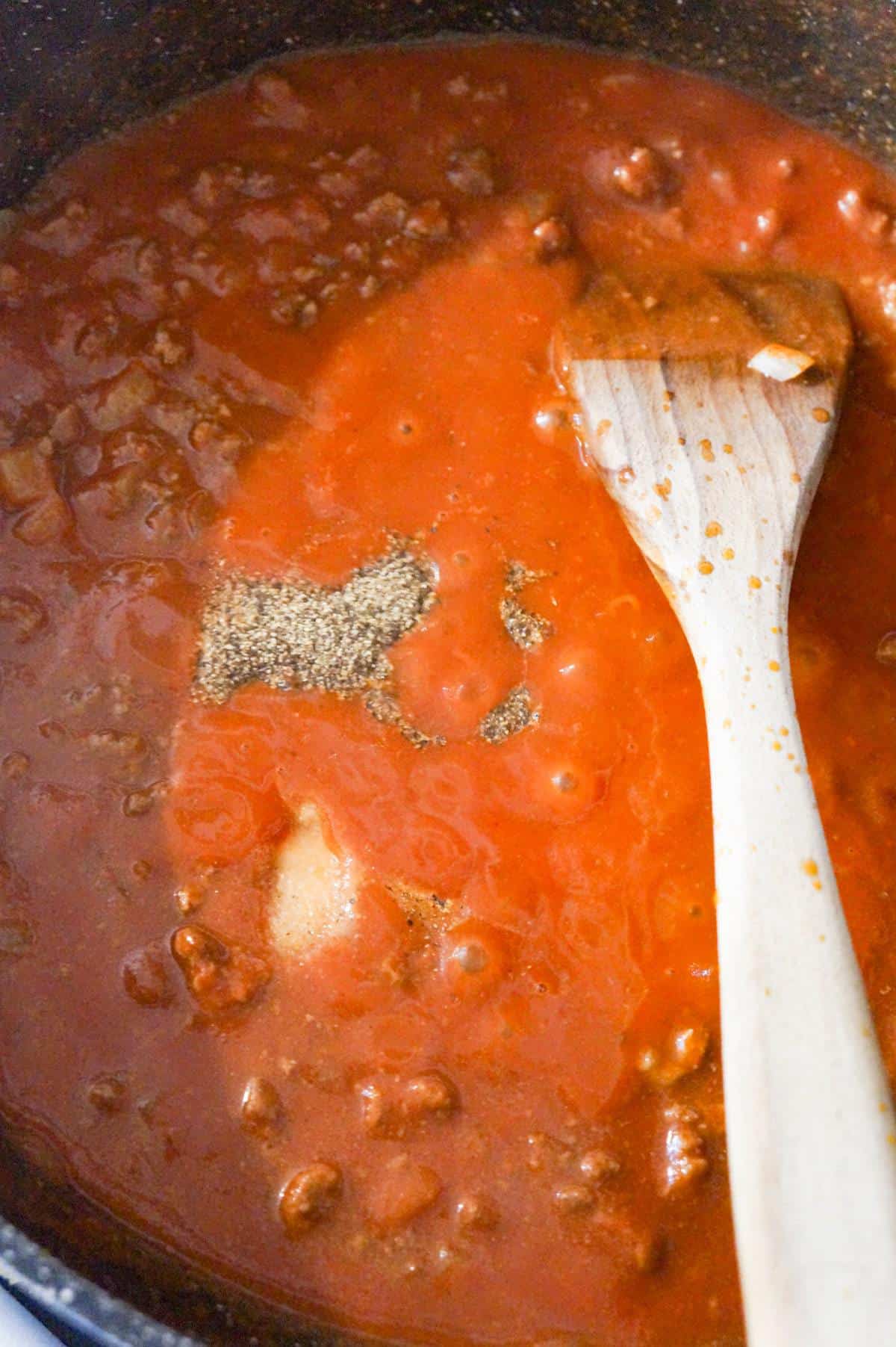 salt and pepper on top of tomato sauce in a saute pan