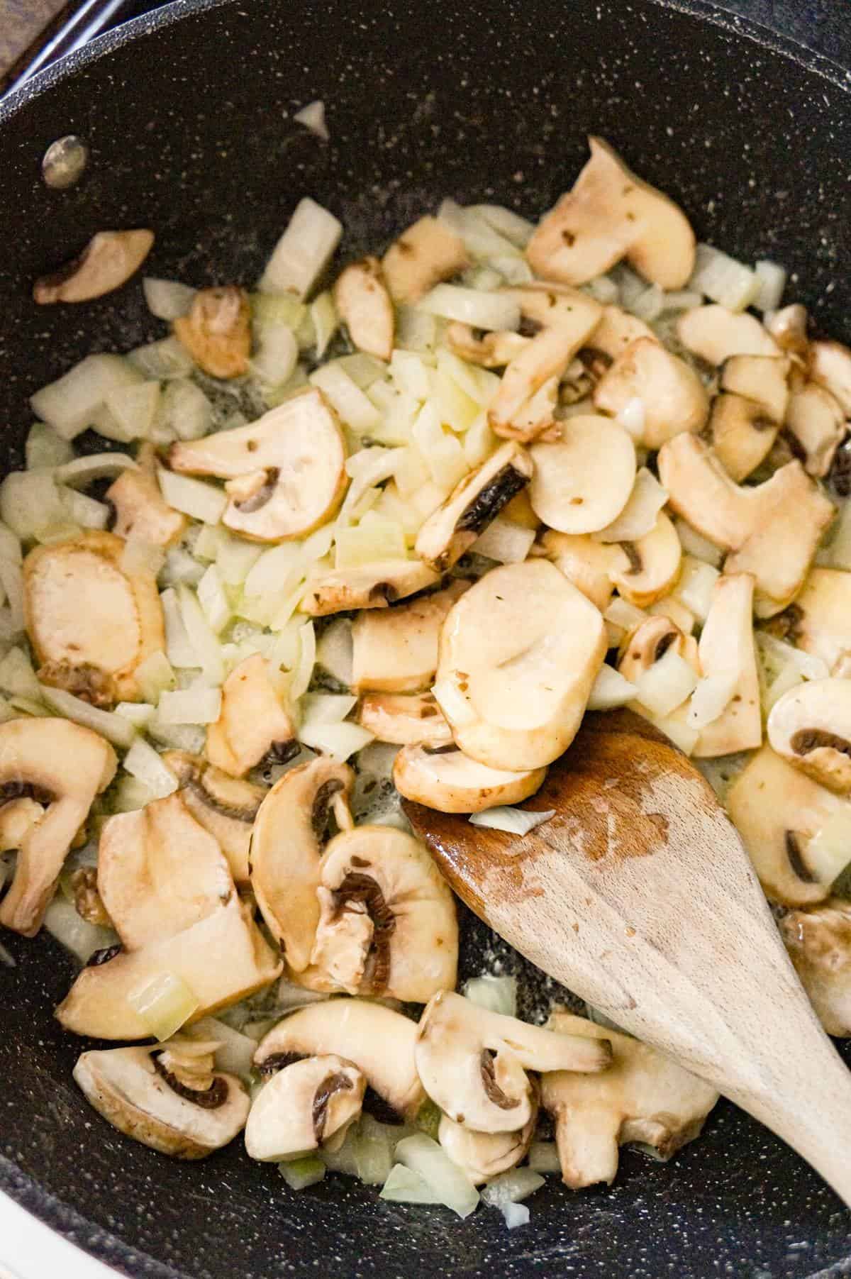 sliced mushrooms and diced onions cooking in a saute pan