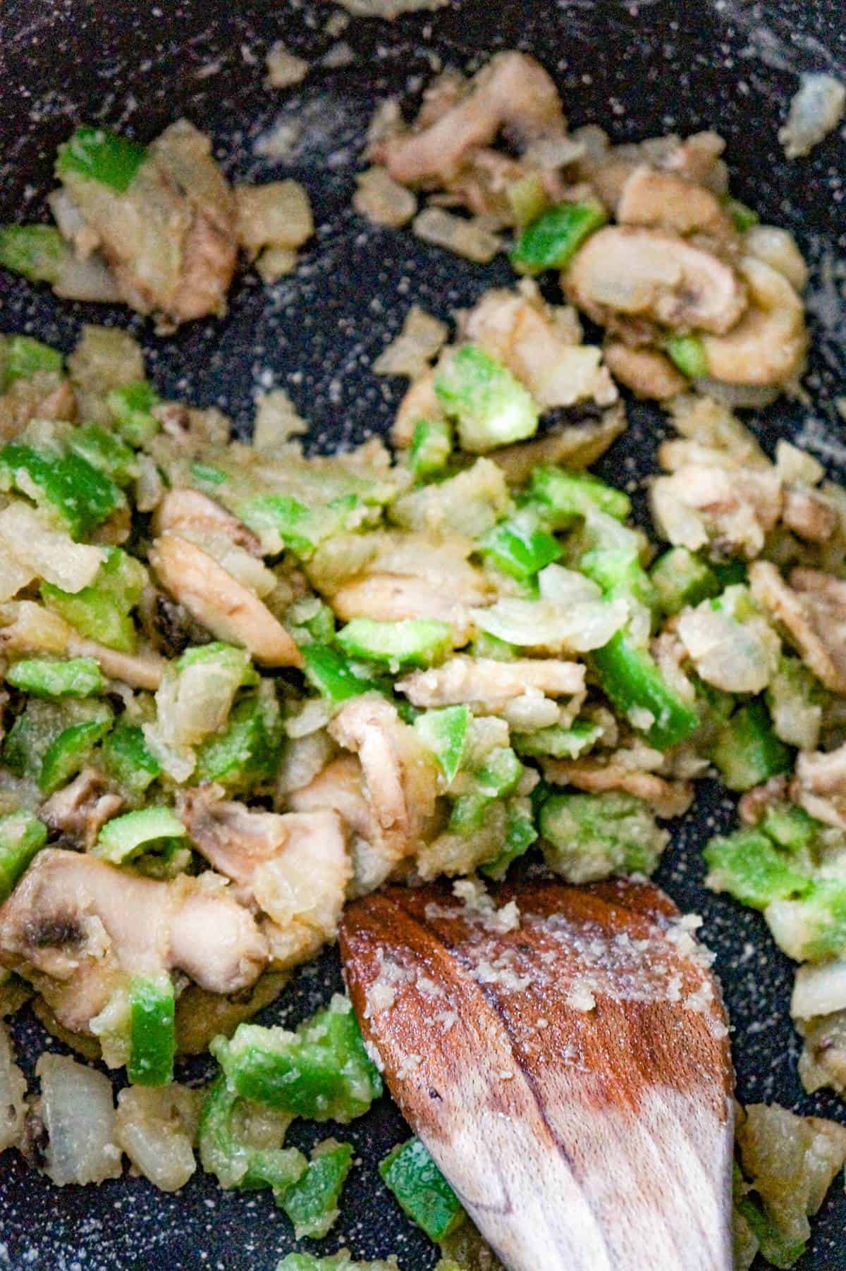 sliced mushrooms and diced green peppers cooking with flour and butter in a saute pan