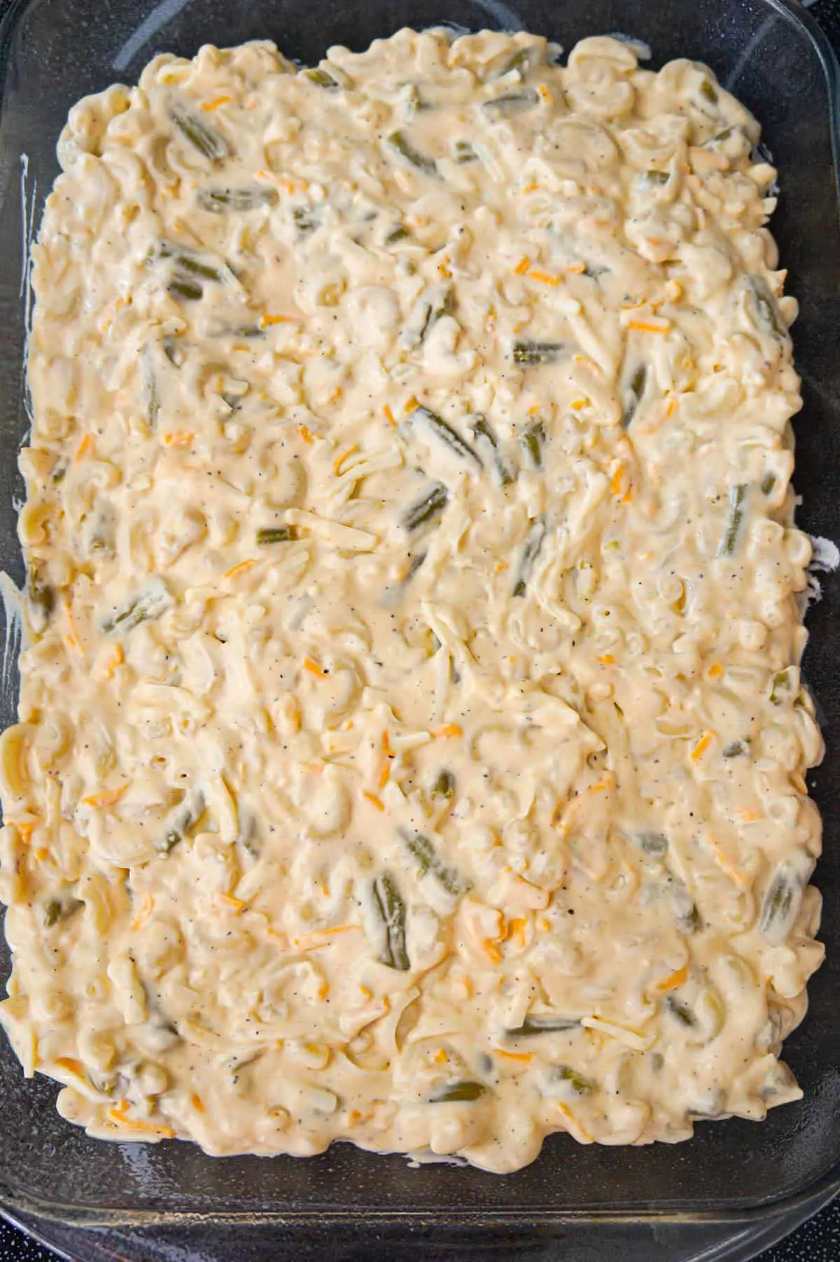 creamy macaroni and cheese mixture with green beans in a baking dish