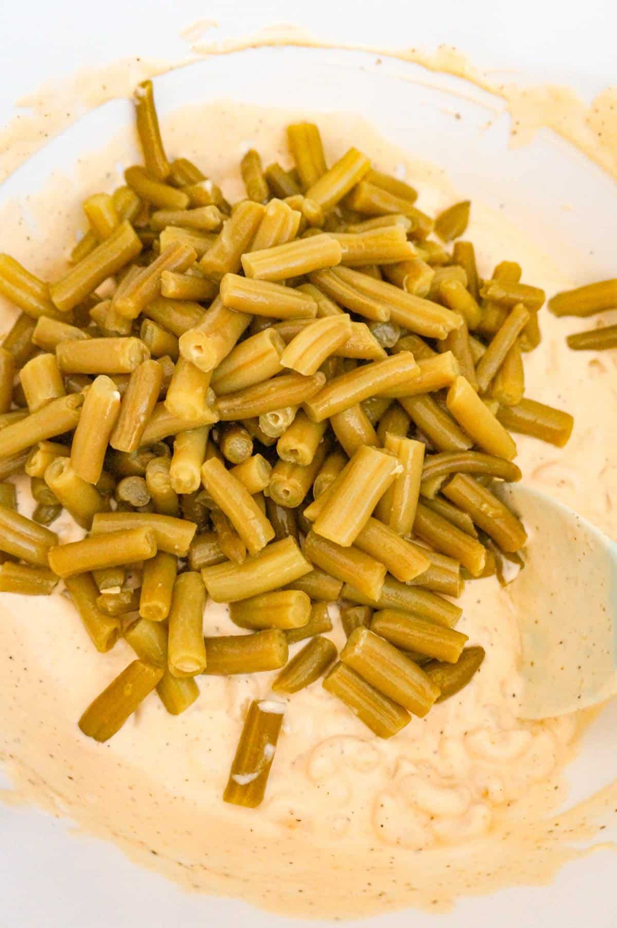 cut green beans on top of cream macaroni mixture in a mixing bowl