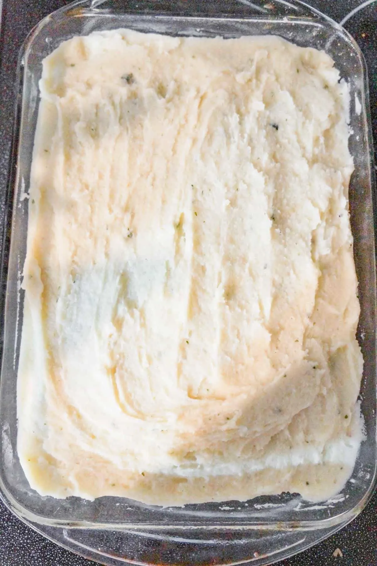 mashed potatoes spread on top of casserole in a baking dish