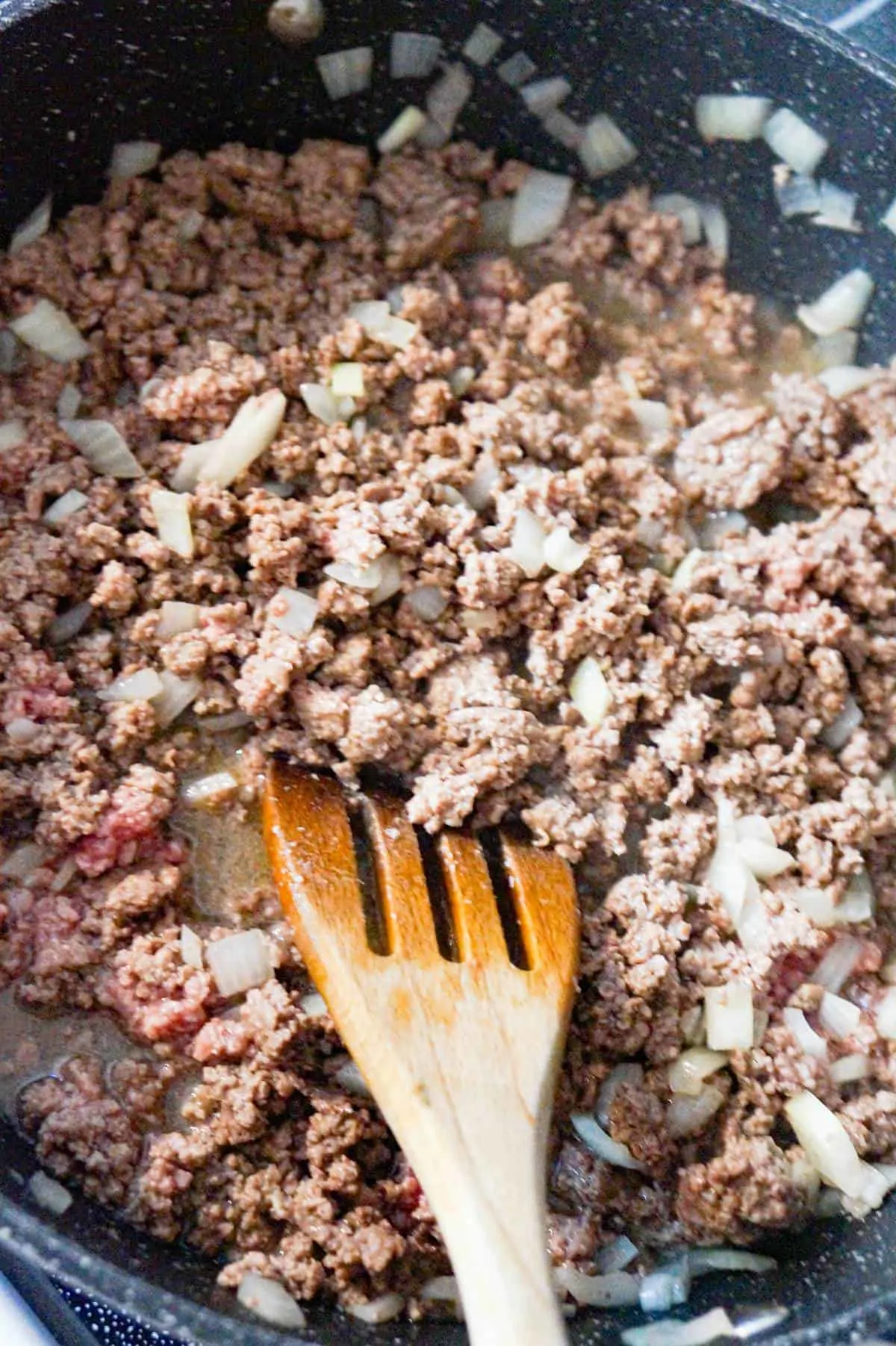ground beef and diced onions cooking in a saute pan