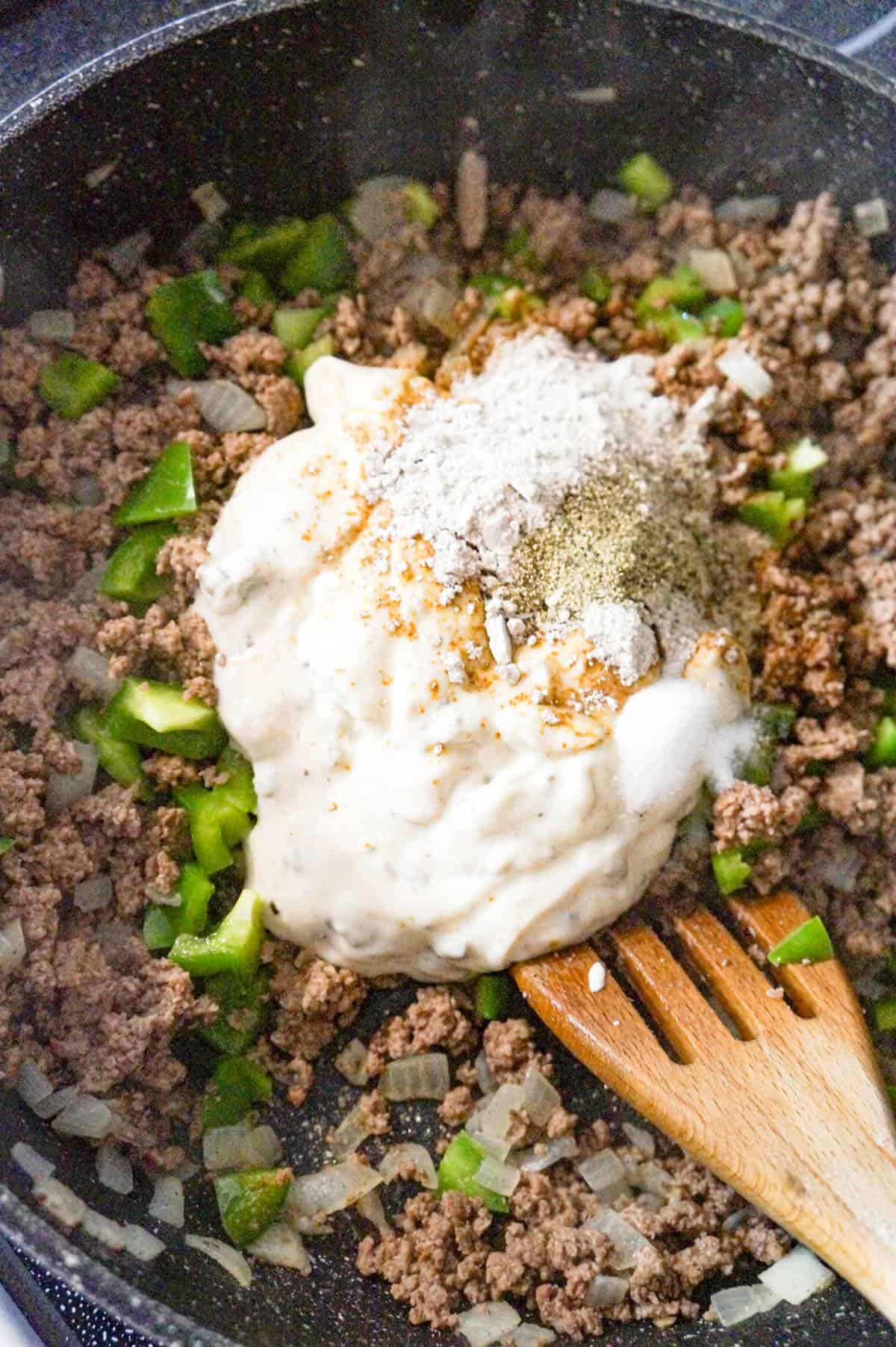 spices and condensed cream of mushroom soup on top of cooked ground beef in a baking dish