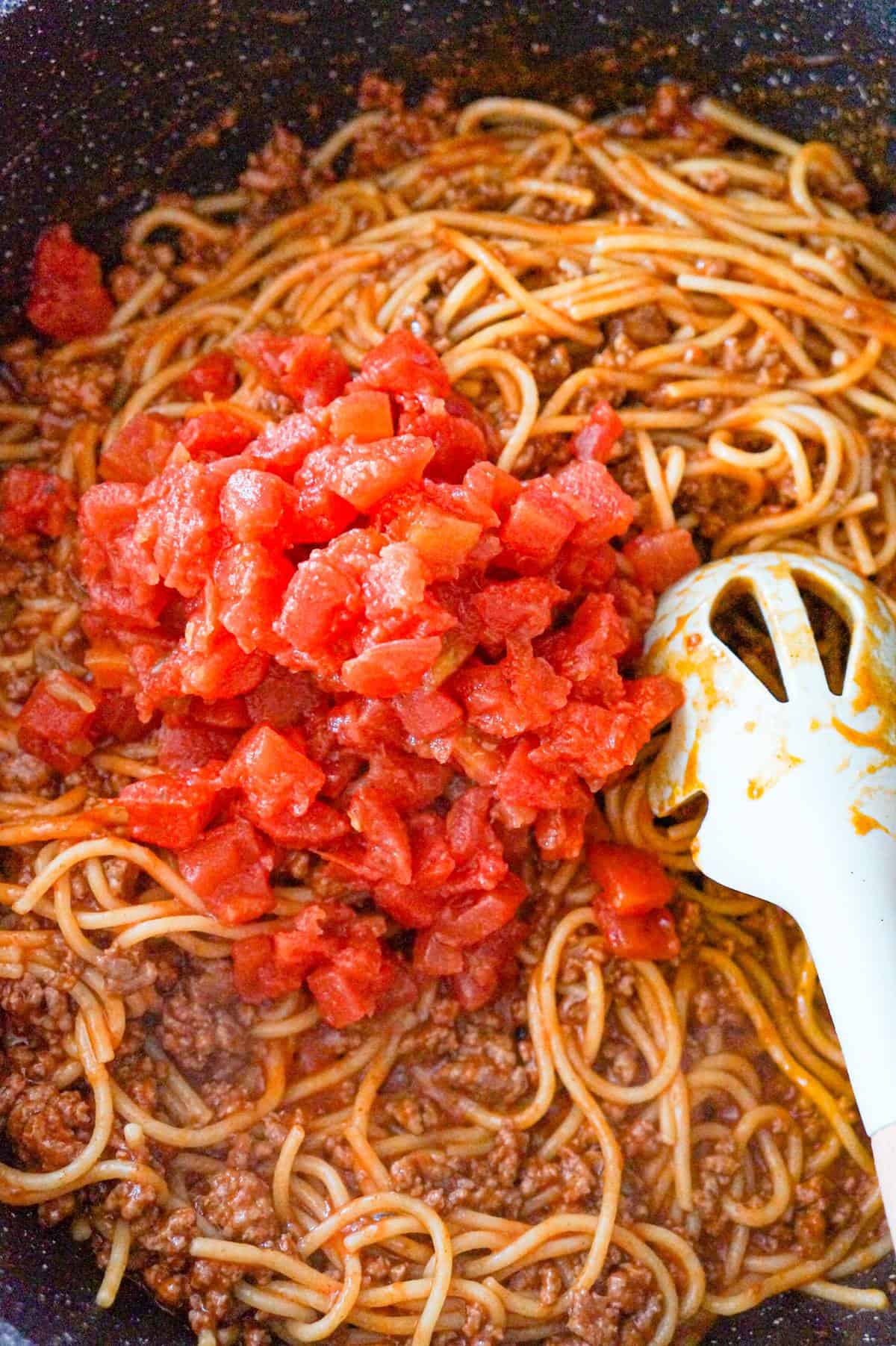 Rotel on top of spaghetti in a saute pan