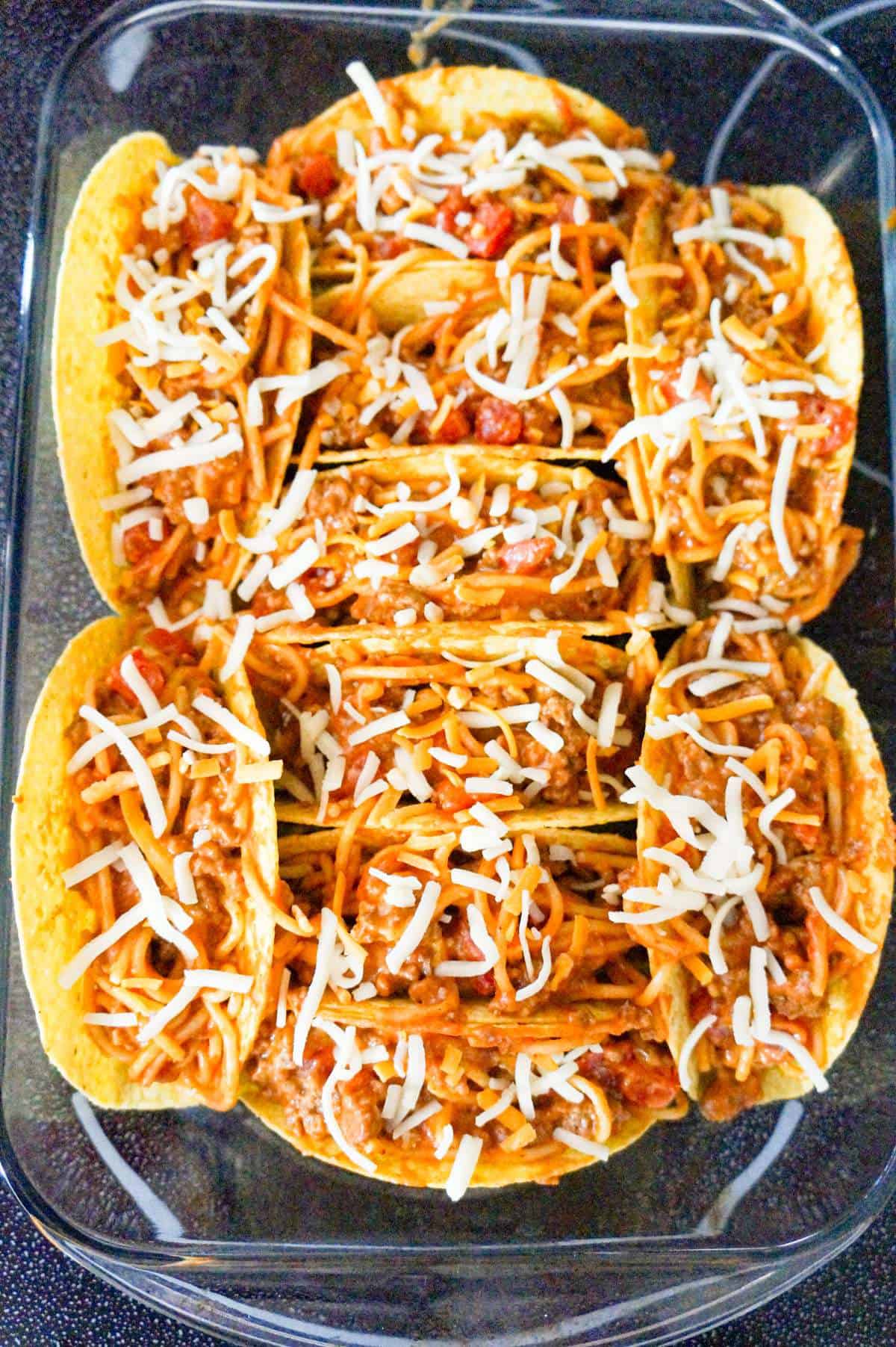 spaghetti tacos with cheese in a pan before baking