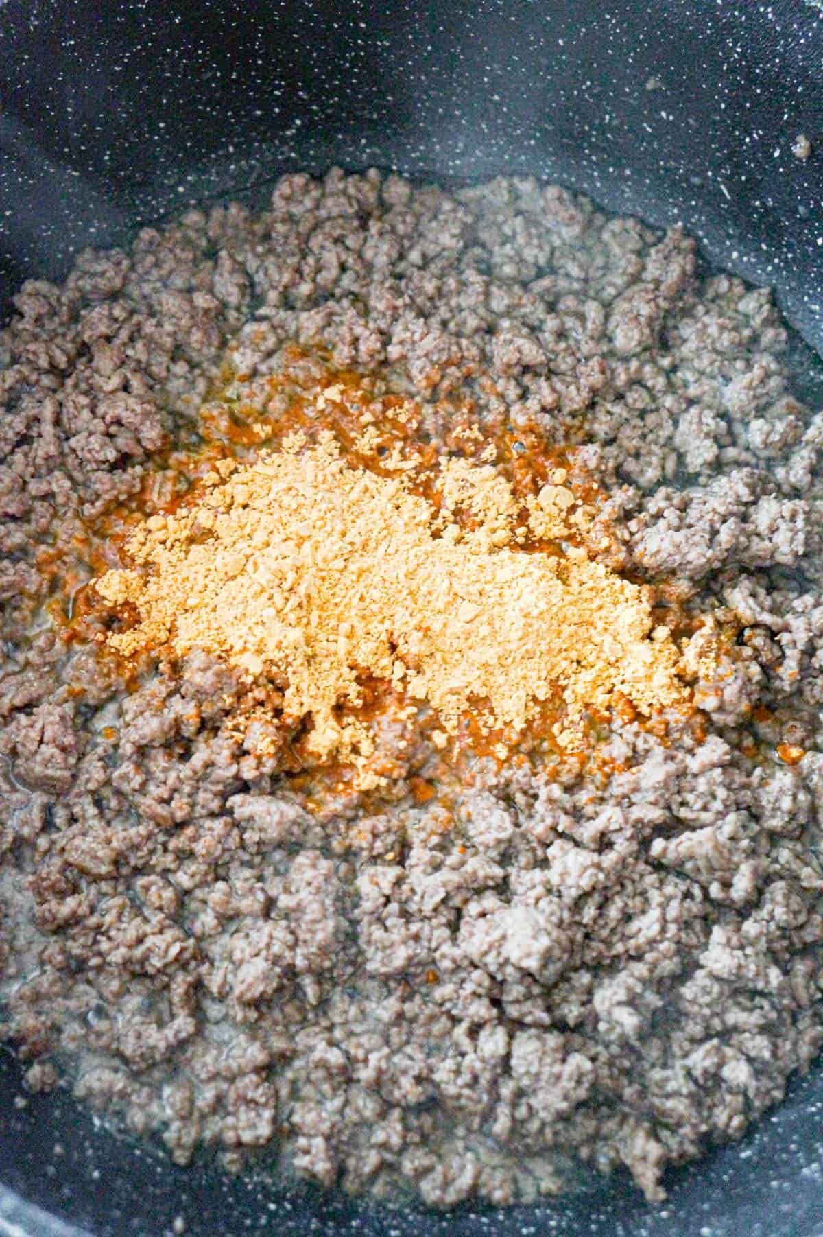taco seasoning on top of ground beef in a saute pan