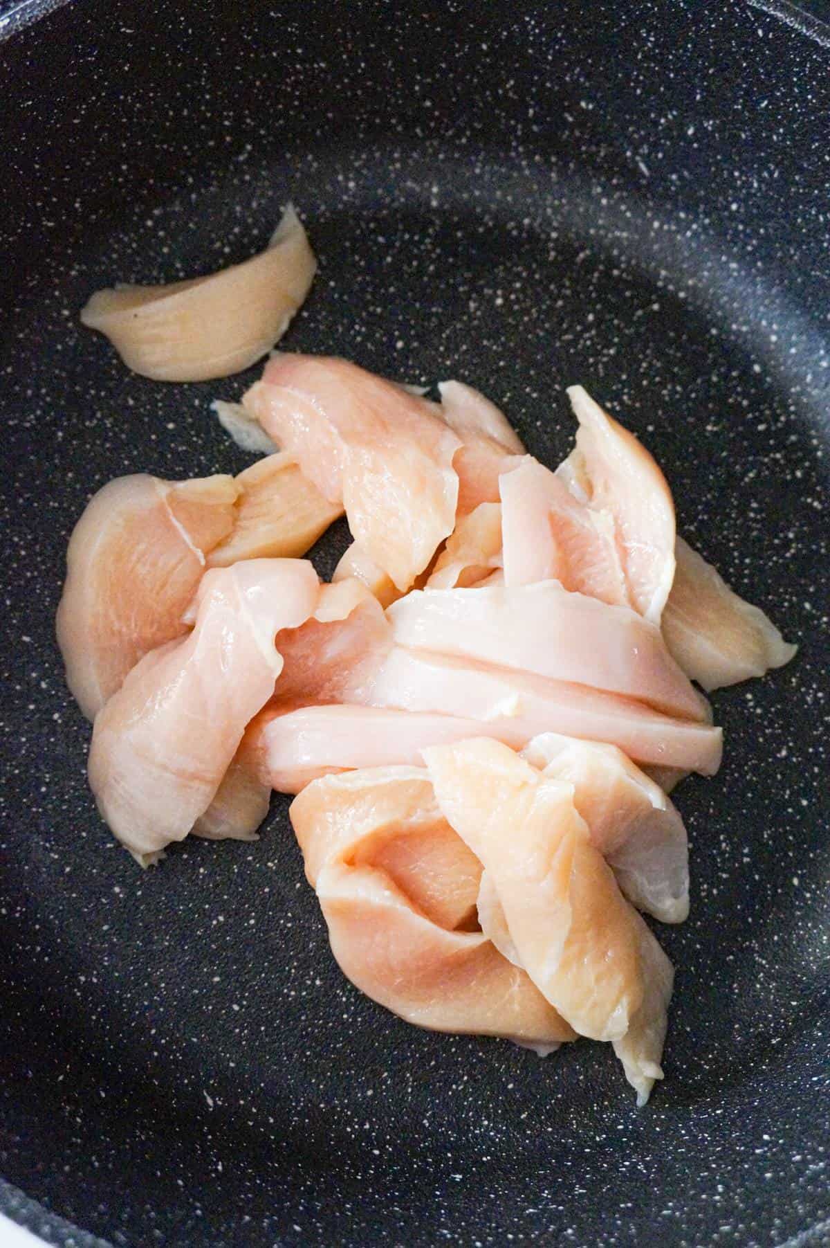 raw chicken breast strips in a saute pan