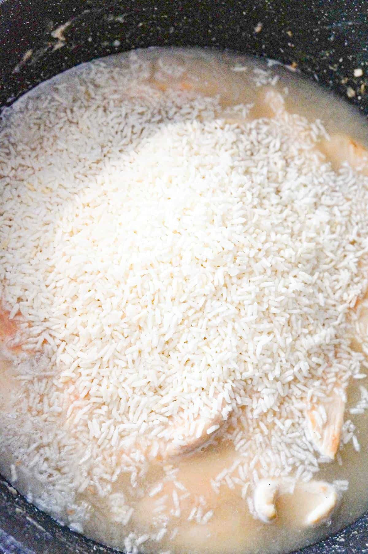 minute rice on top of broth and chicken in a saute pan