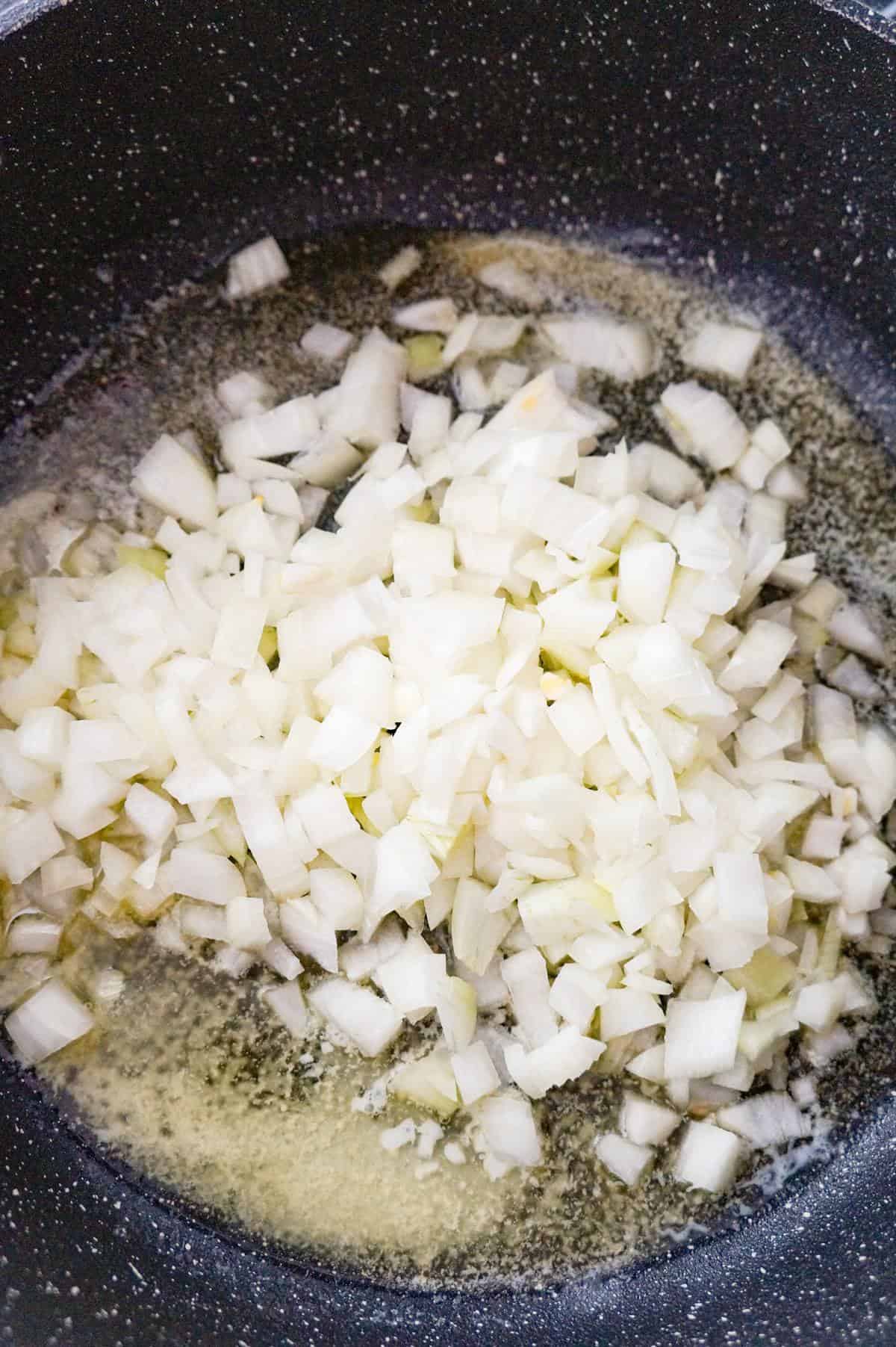 diced onions added to a pot with melted butter