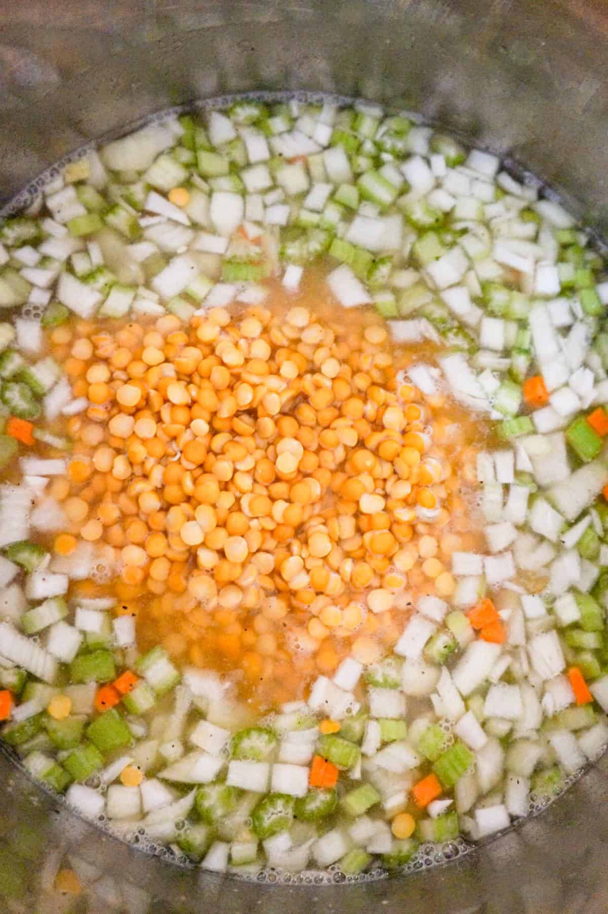 yellow split peas on top of diced vegetables in broth in an Instant Pot
