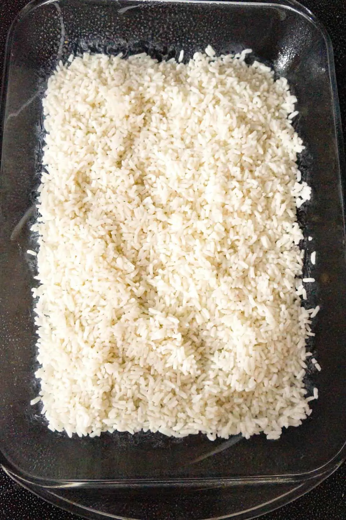 cooked white rice in the bottom of a casserole dish