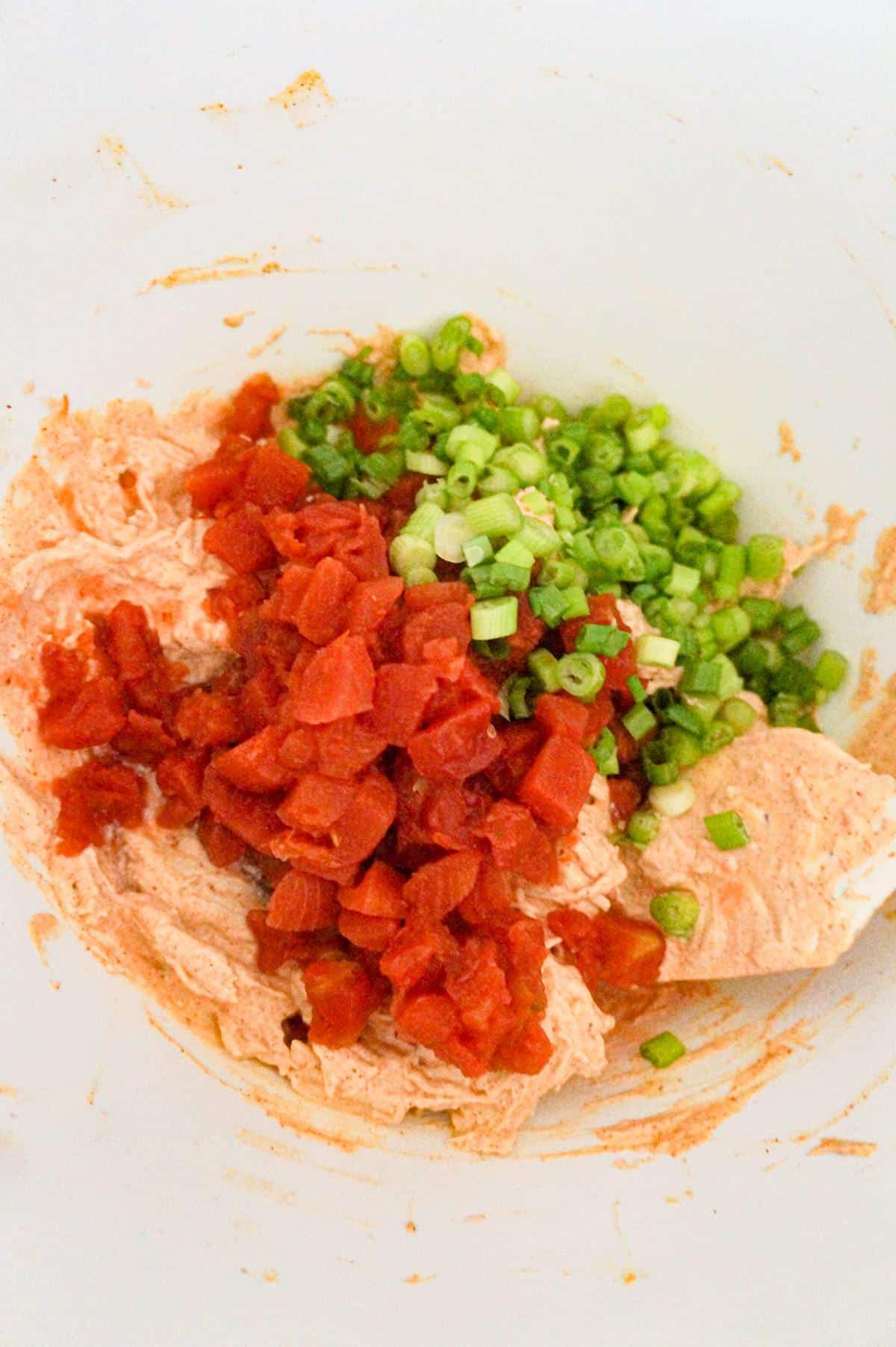 Rotel and chopped green onions on top of chicken mixture in a mixing bowl