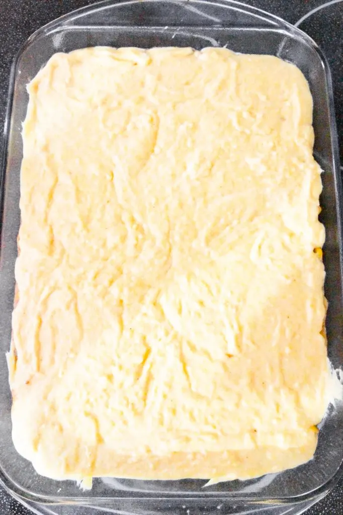 cornbread batter on top of casserole in a baking dish