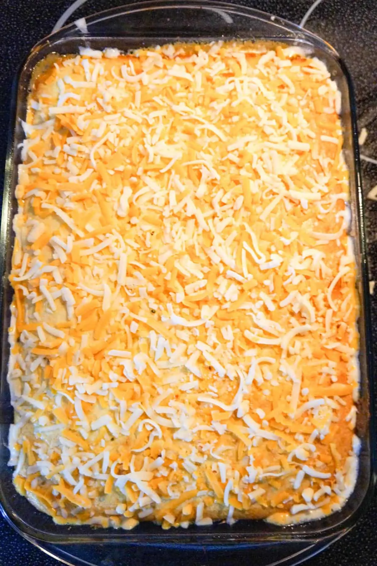 shredded cheese on top of cornbread in a baking dish