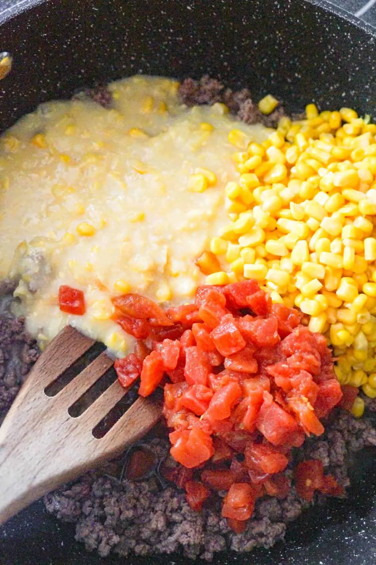 creamed corn, corn and Rotel on top of cooked ground beef in a saute pan