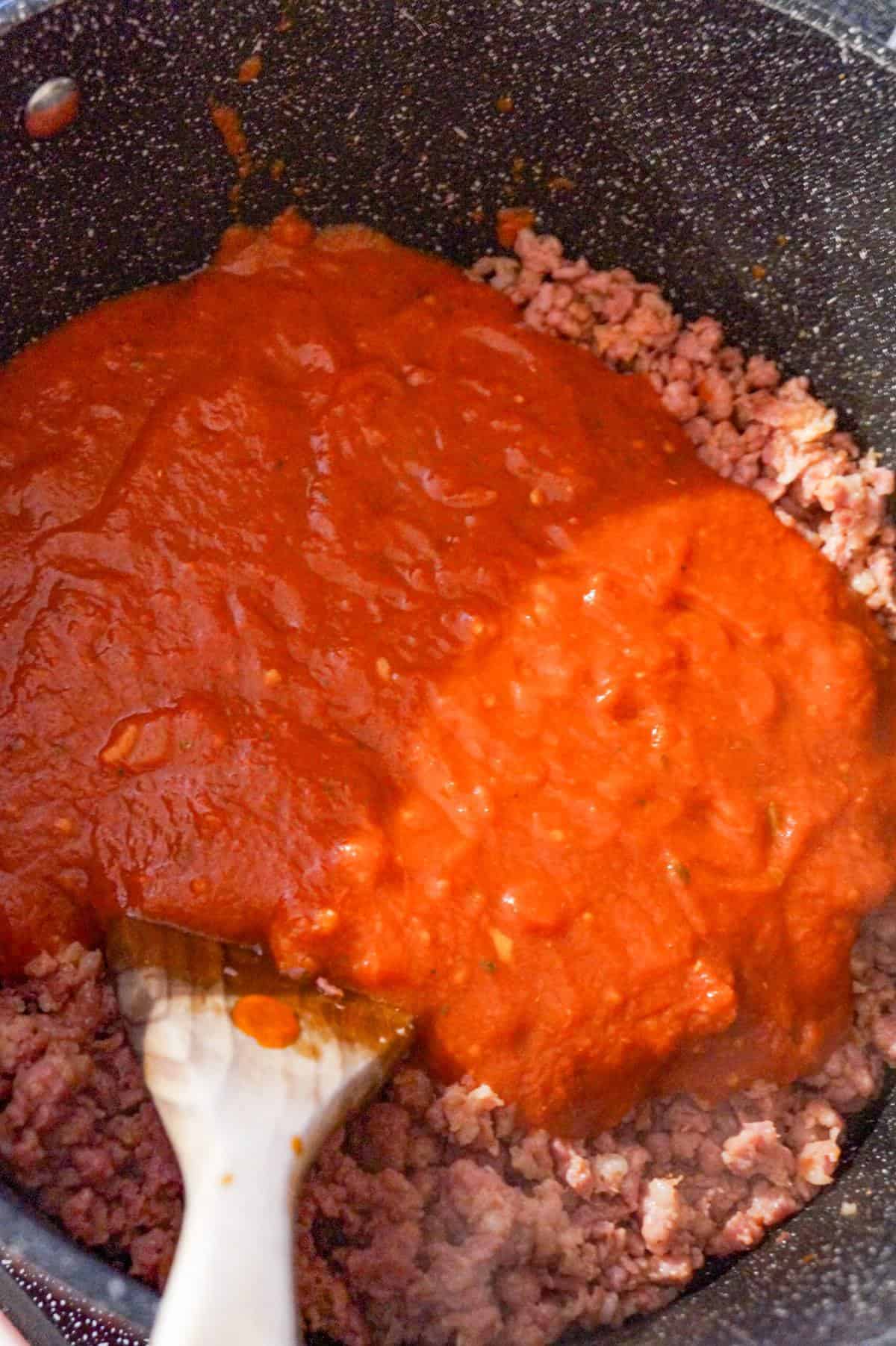 marinara on top of cooked ground sausage in a large pot